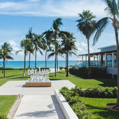 Palm tree lined lawn and Dreams Jade sign overlooking the ocean, Riviera Maya