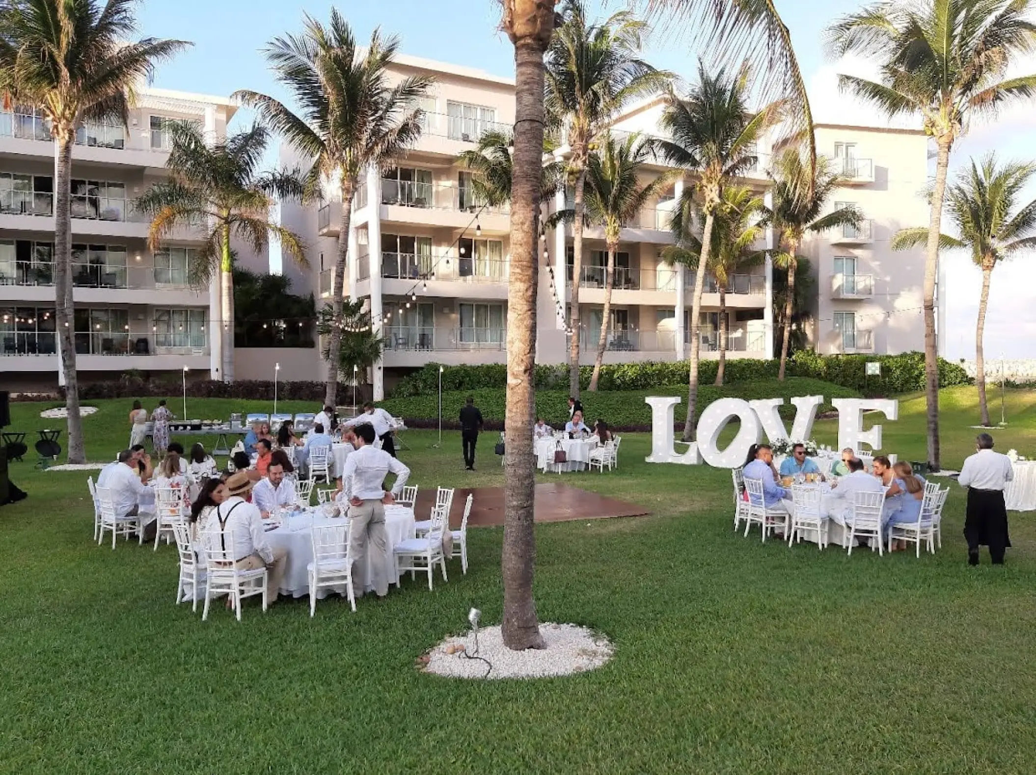 Outdoor garden wedding reception with white LOVE letters and guest tables at Dreams Jade, Riviera Maya
