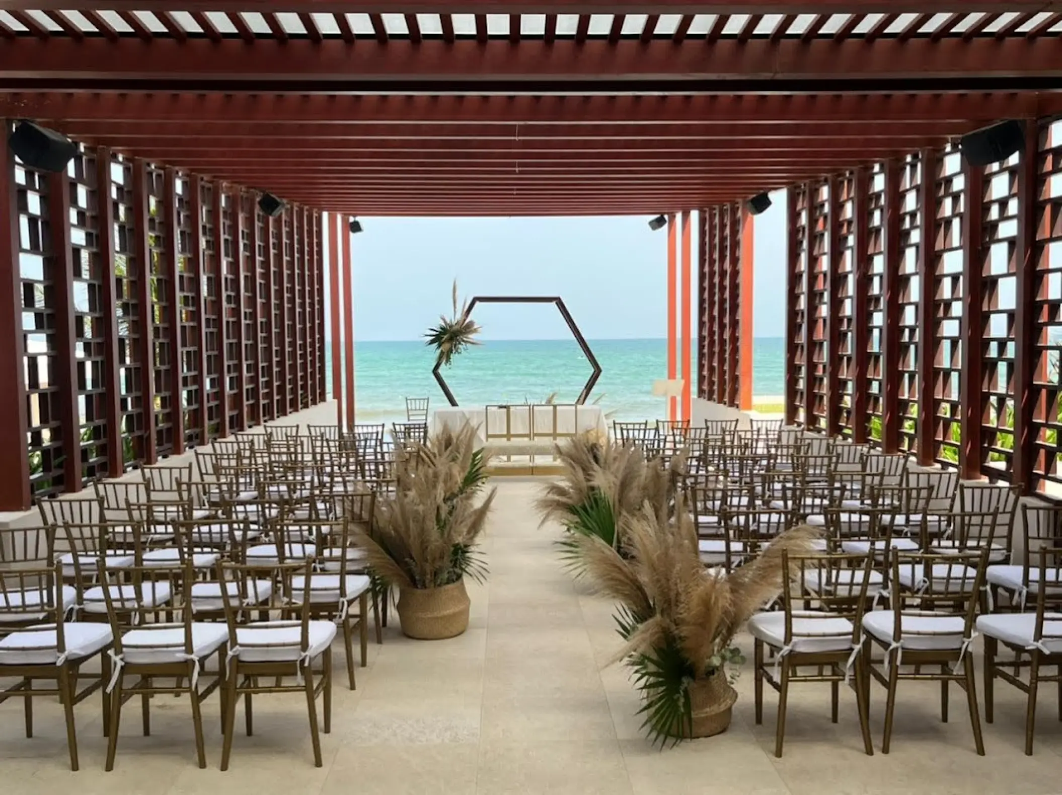 Pergola wedding ceremony setup with pampas grass and hexagon arch at Dreams Jade, Riviera Maya