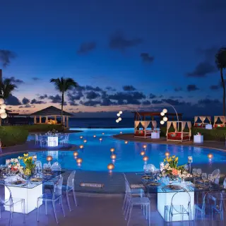 Nighttime wedding reception around a lit pool at Dreams Jade, Riviera Maya