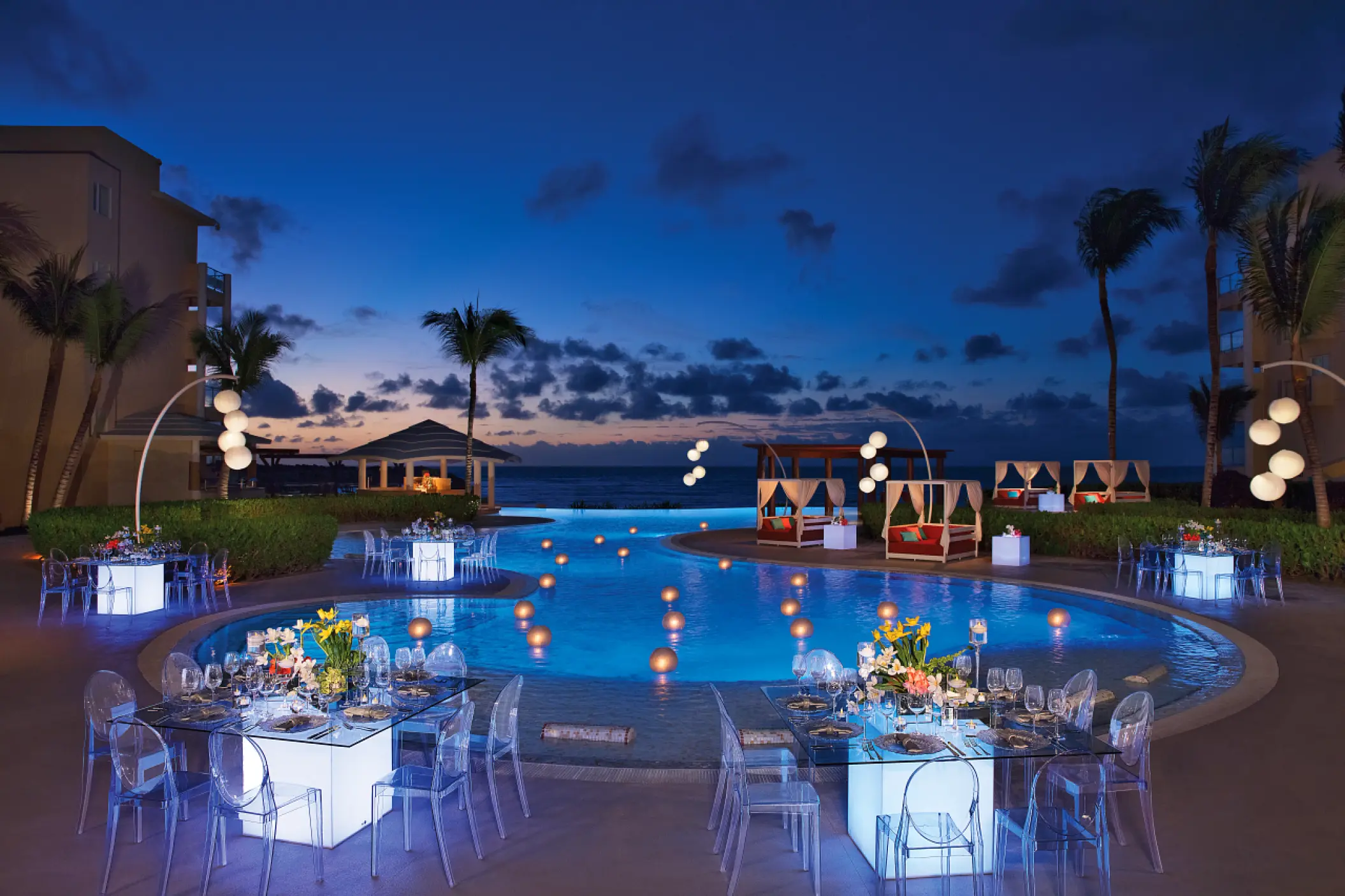 Nighttime wedding reception around a lit pool at Dreams Jade, Riviera Maya
