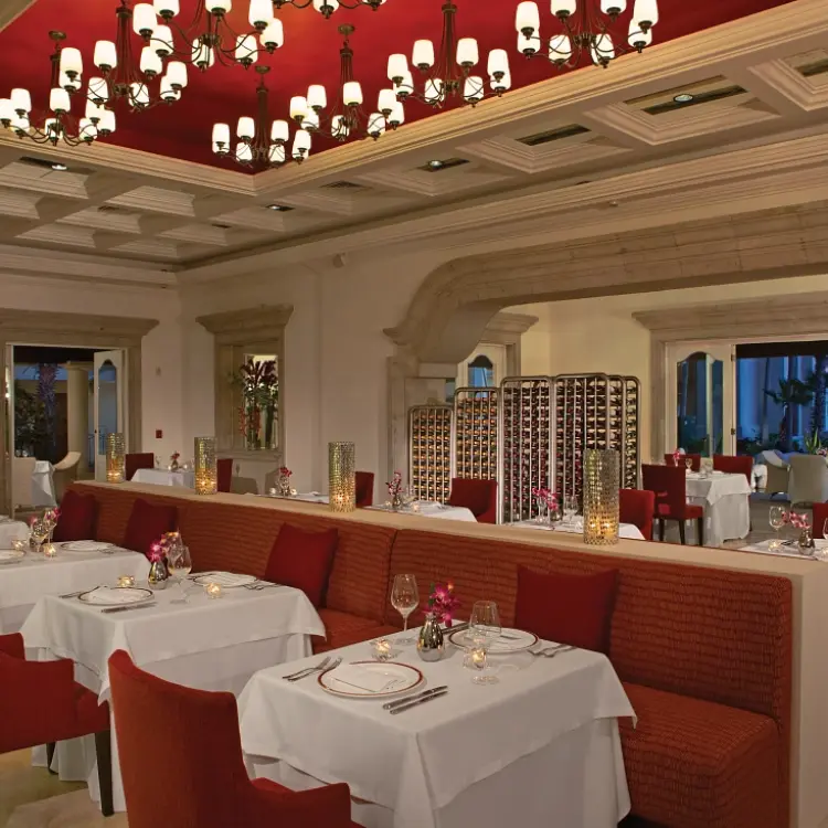 Bordeaux restaurant with white linens and red chairs at Dreams Los Cabos, Cabo San Lucas