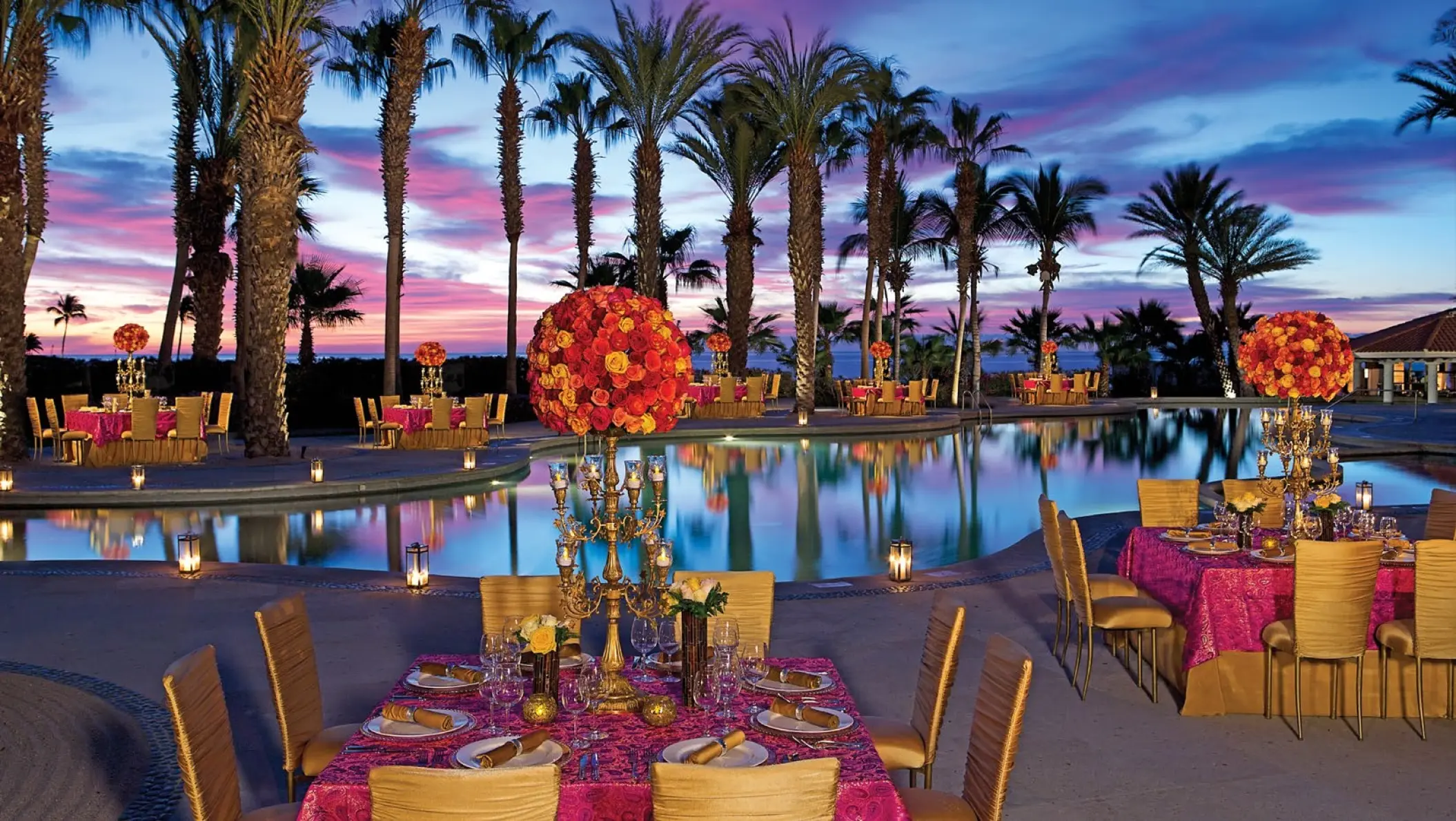 Outdoor wedding reception setup with pink linens around the pool at Dreams Los Cabos, Cabo San Lucas