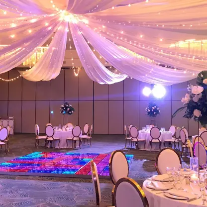Indoor ballroom wedding reception with fabric ceiling draping and a lighted dance floor at Dreams Macao Beach, Punta Cana
