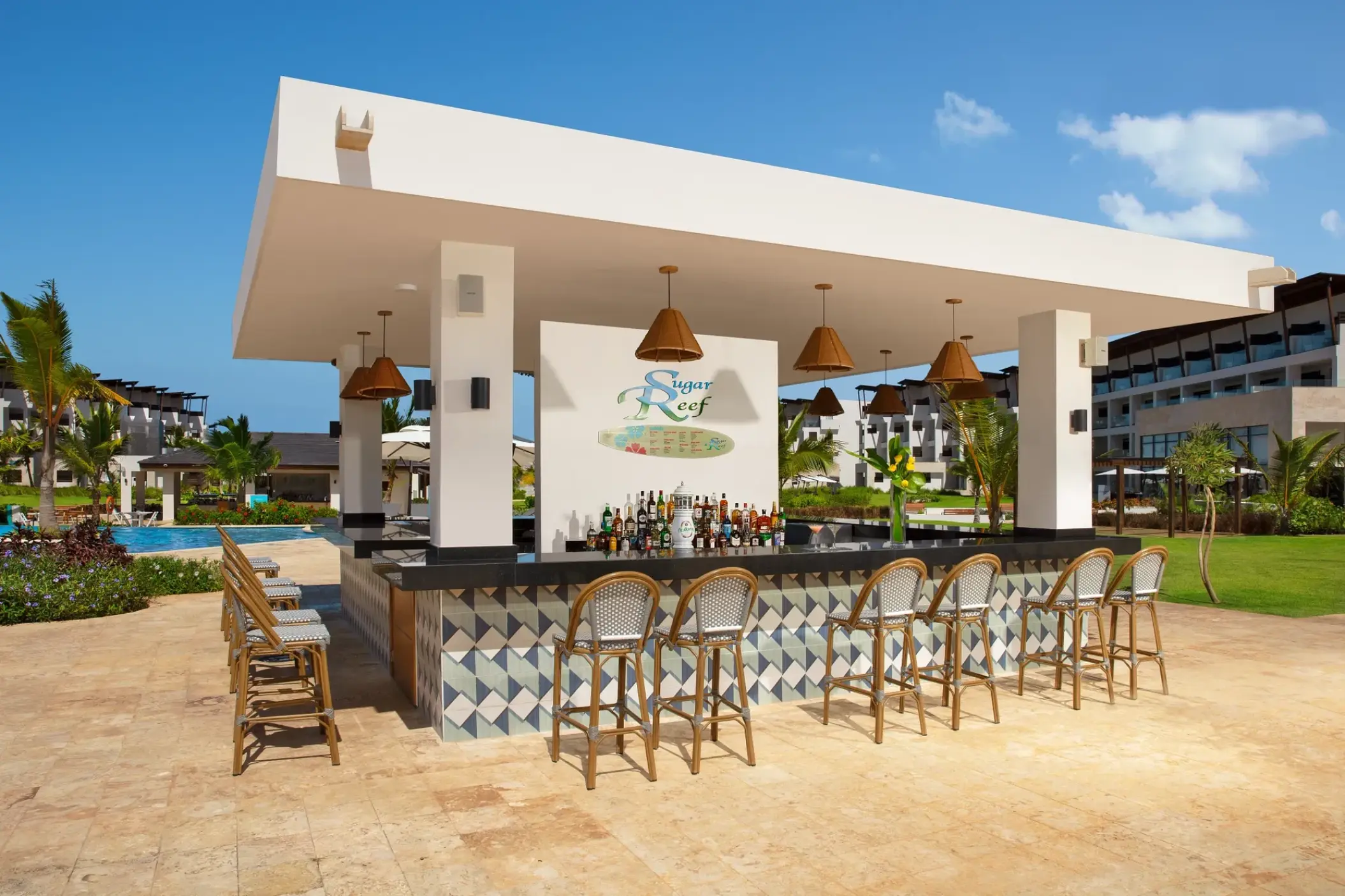 Sugar Reef poolside bar with wicker stools and tiled counter at Dreams Macao Beach, Punta Cana
