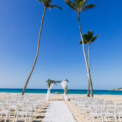 Beachfront wedding ceremony with white chairs and floral arch at Dreams Macao Beach, Punta Cana