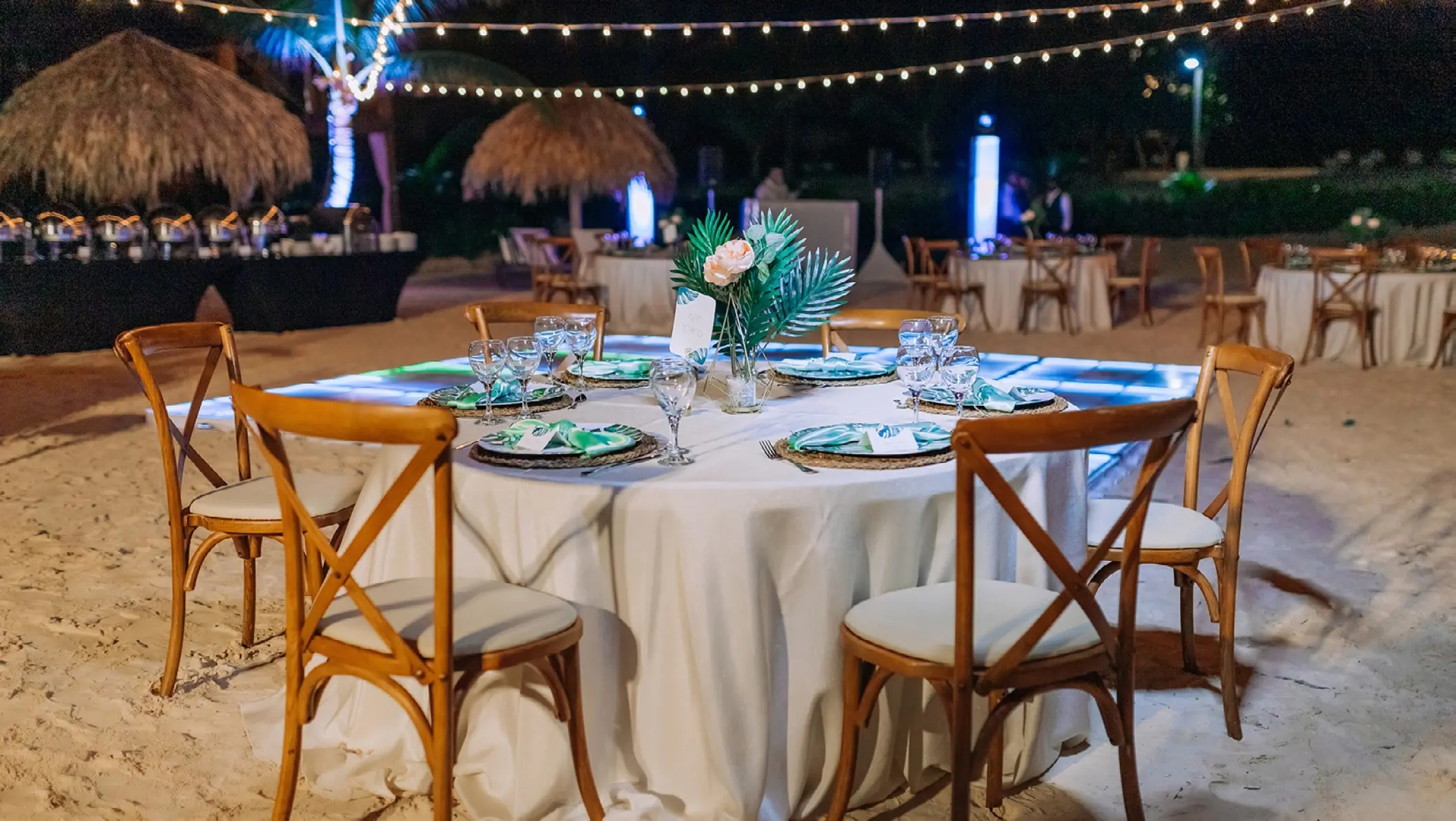 Beach wedding reception with cross-back chairs and string lights at Dreams Macao Beach, Punta Cana