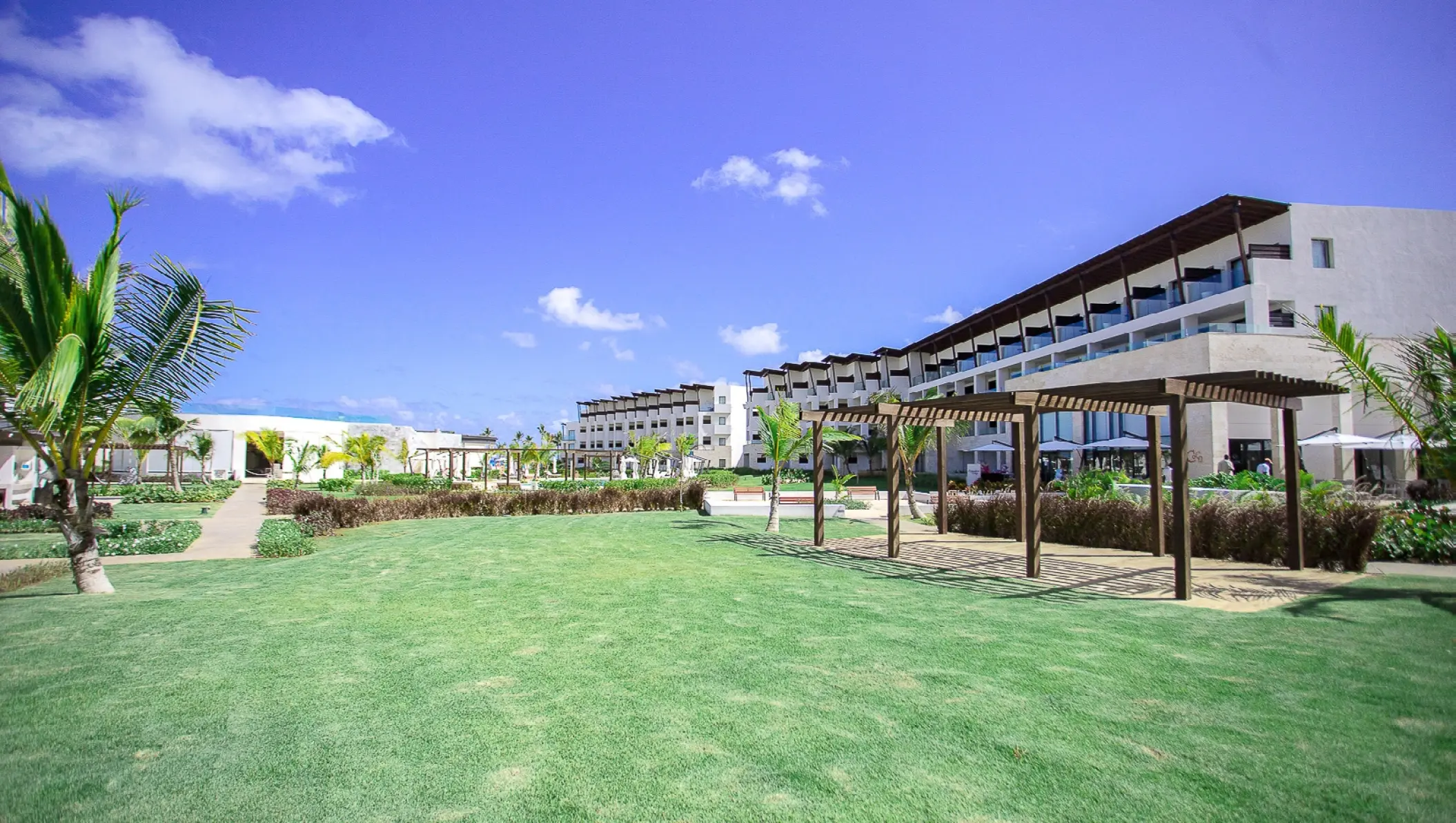 Himitsu garden terrace with wooden pergolas and green lawn at Dreams Macao Beach, Punta Cana