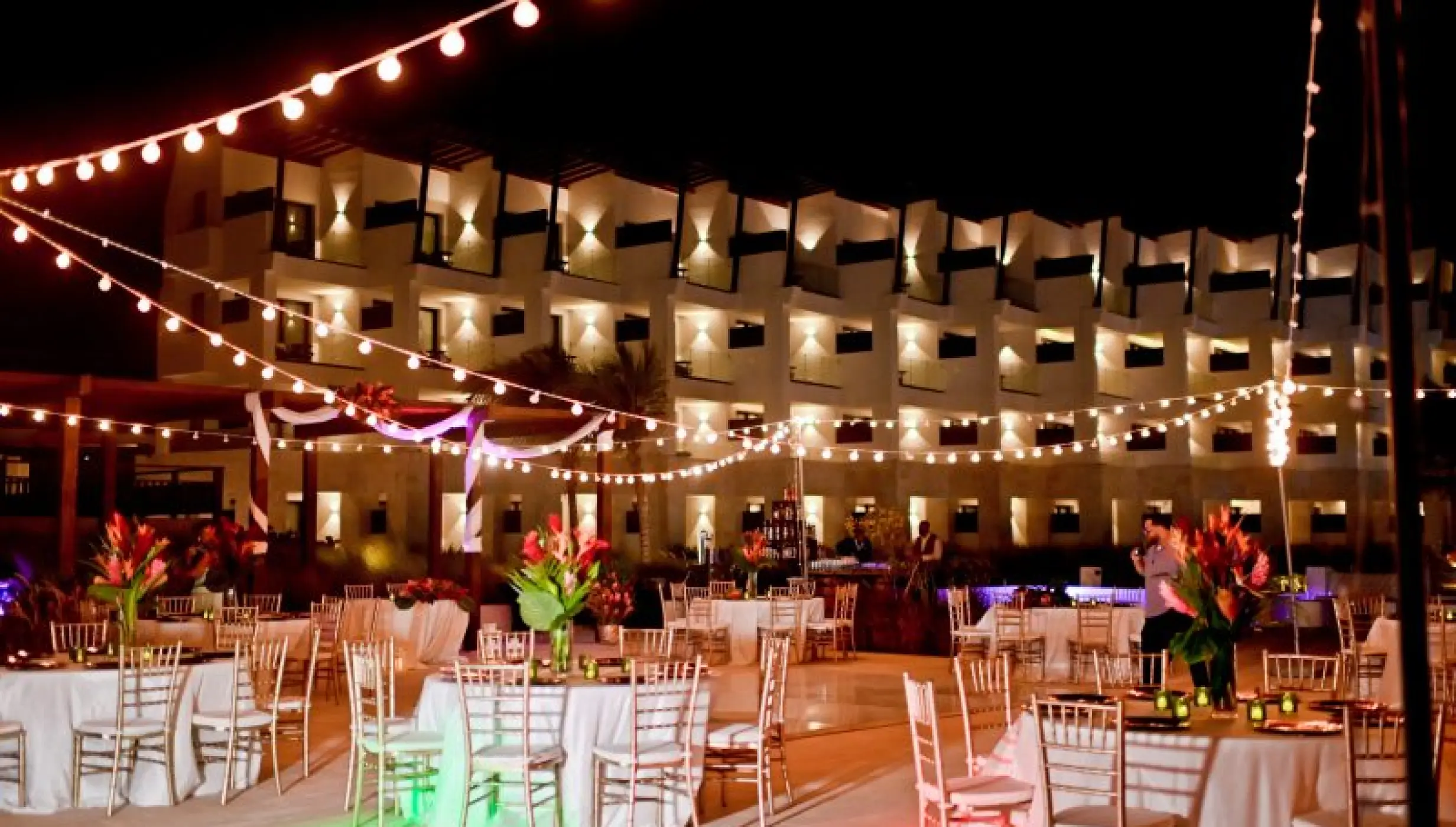 Nighttime wedding reception at Dreams Macao Beach plaza with string lights and round tables, Punta Cana
