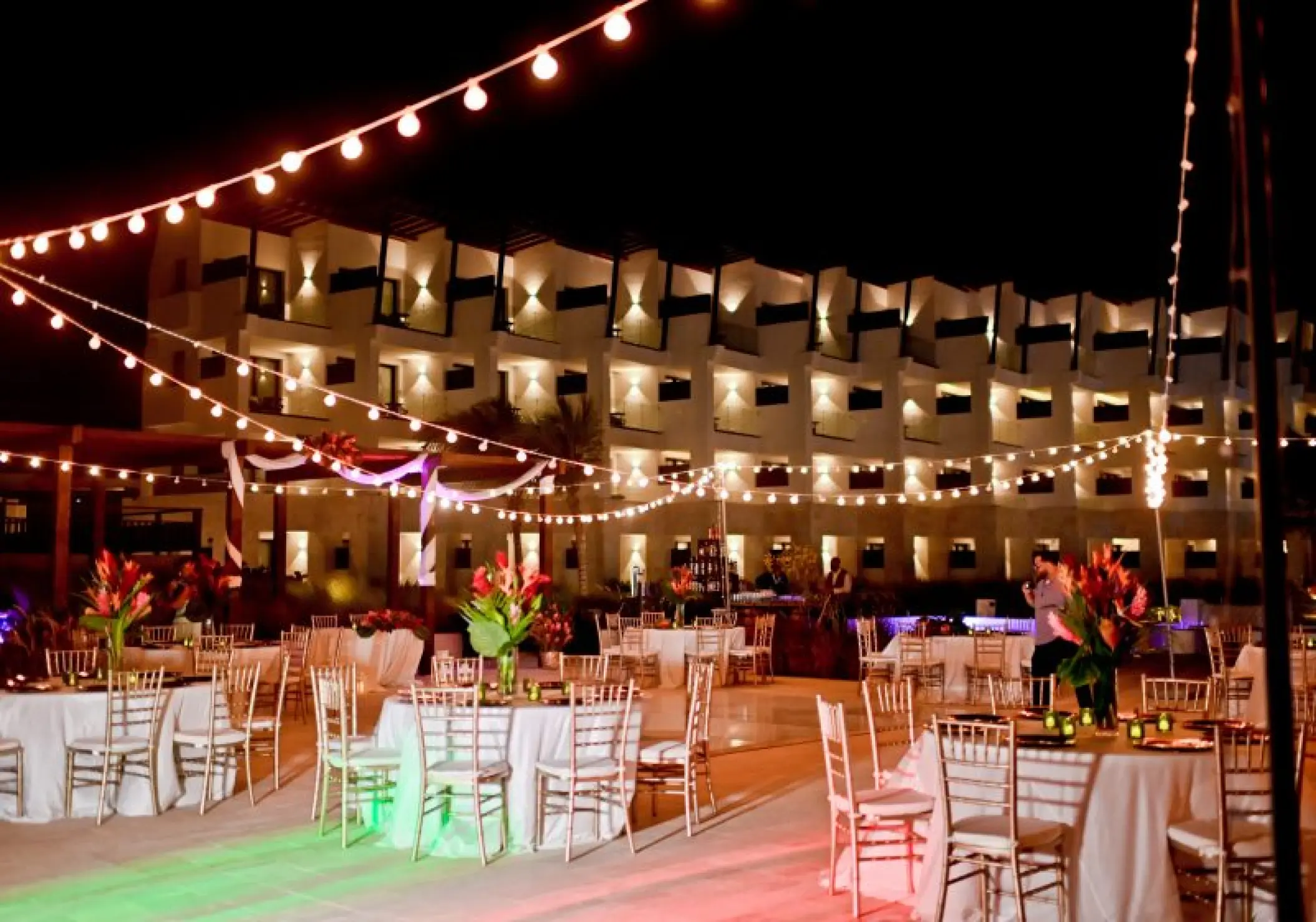 Nighttime wedding reception at Dreams Macao Beach plaza with string lights and round tables, Punta Cana