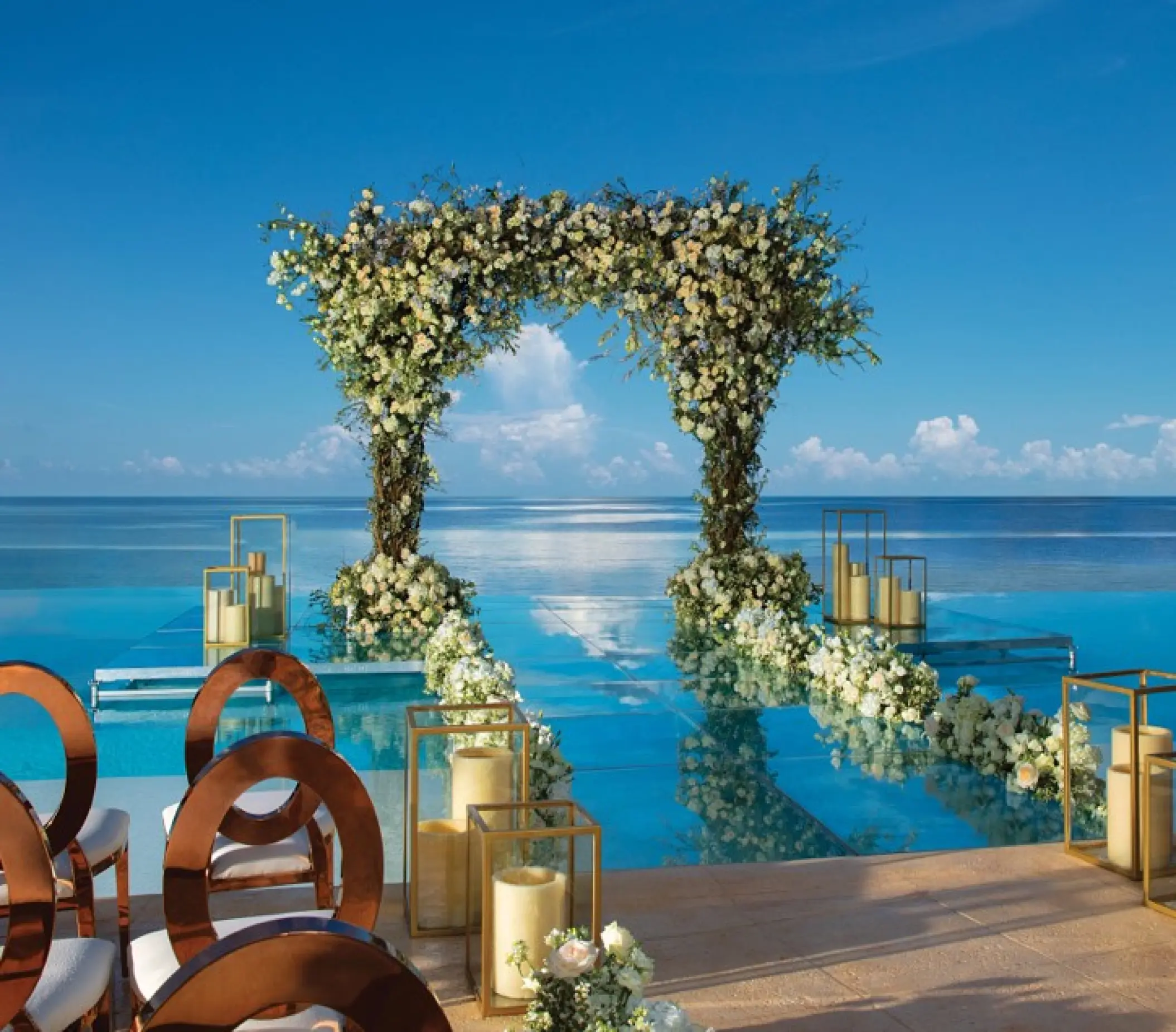 Waterfront wedding ceremony with floral arch and glass aisle over the pool at Dreams Natura, Riviera Maya