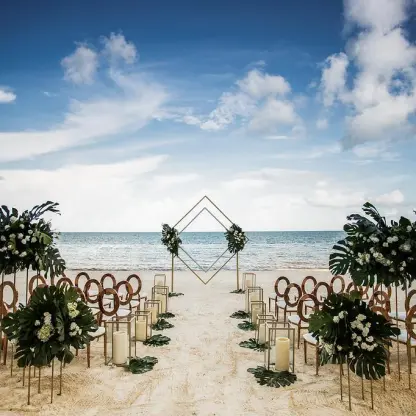 Beachfront wedding ceremony with geometric arch and tropical floral arrangements at Dreams Natura, Riviera Maya