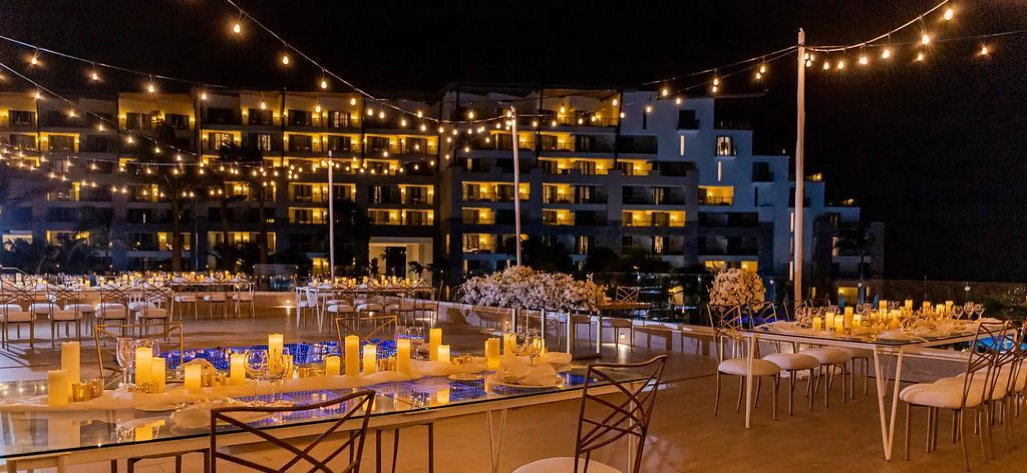 Rooftop wedding reception at Dreams Natura, Riviera Maya with string lights and candlelit tables at night