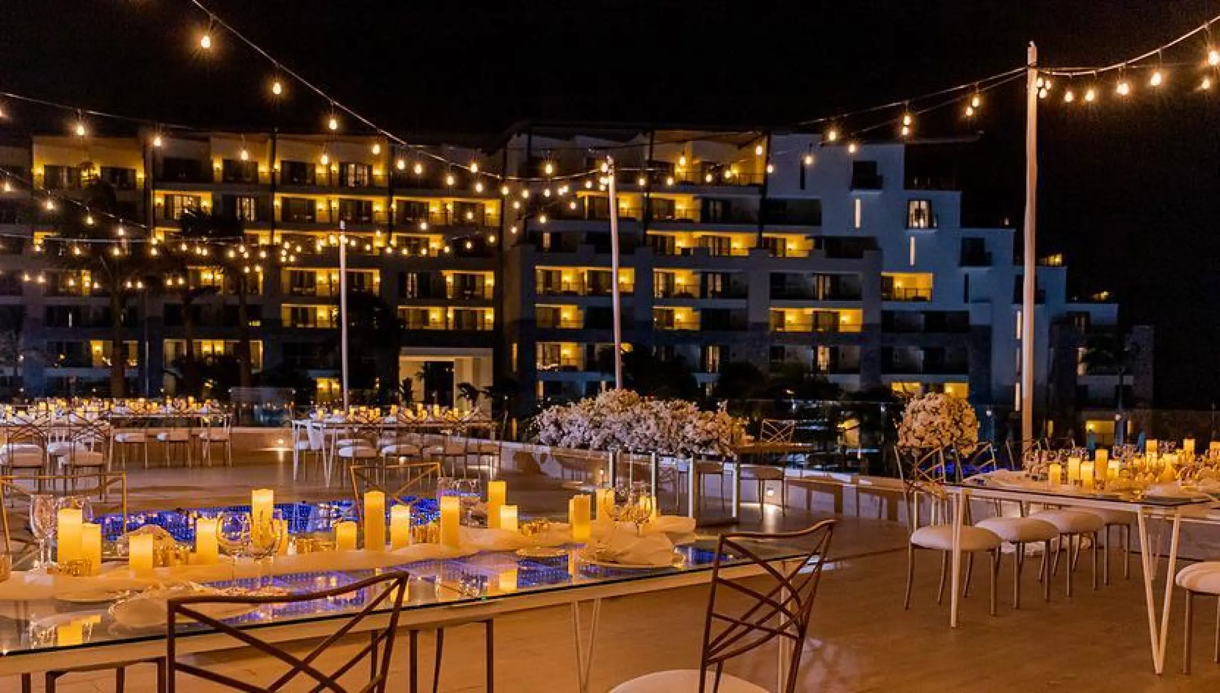 Rooftop wedding reception at Dreams Natura, Riviera Maya with string lights and candlelit tables at night