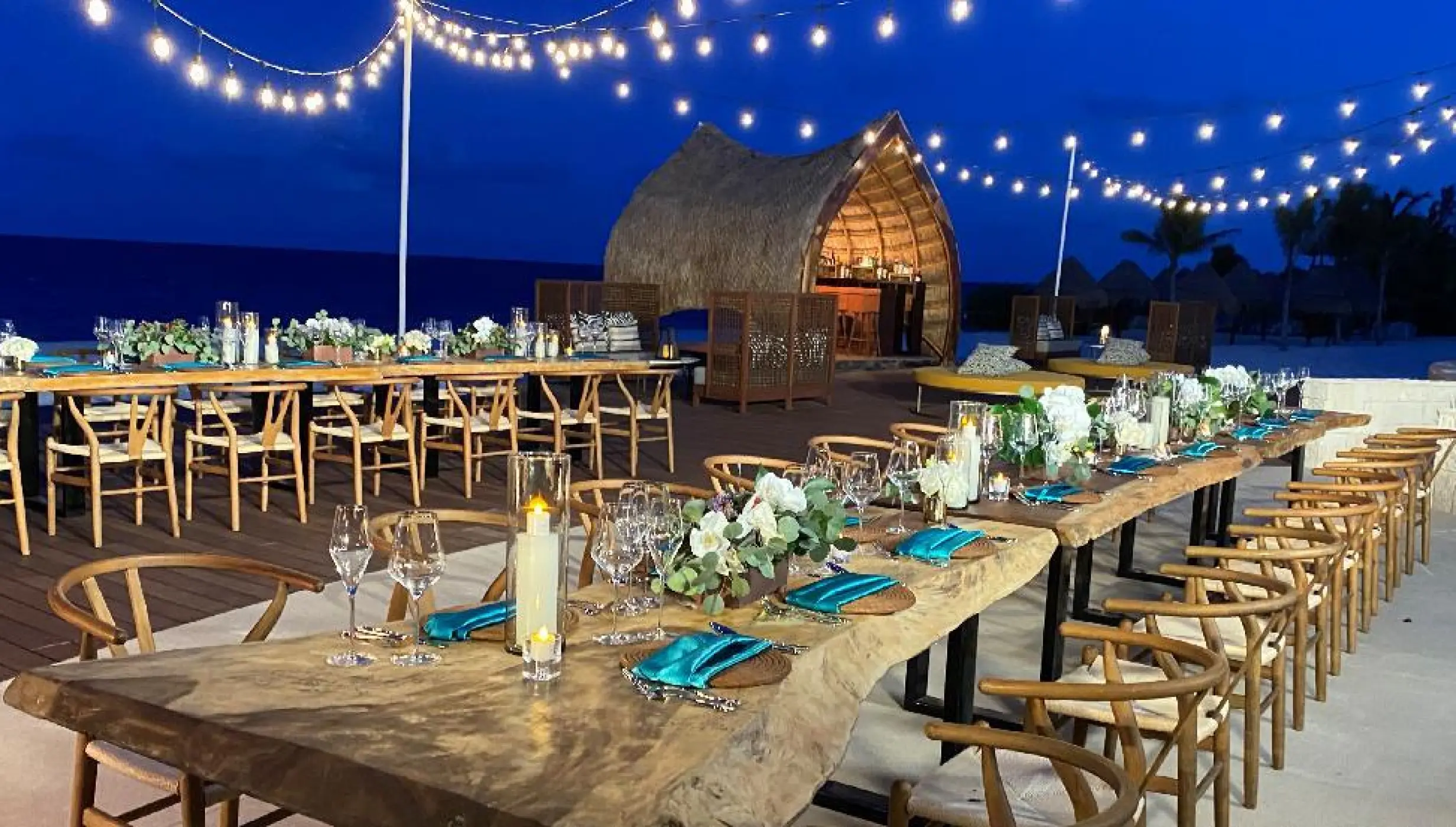Evening wedding reception on a wooden deck with string lights at Dreams Natura, Riviera Maya