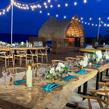 Evening wedding reception on a wooden deck with string lights at Dreams Natura, Riviera Maya
