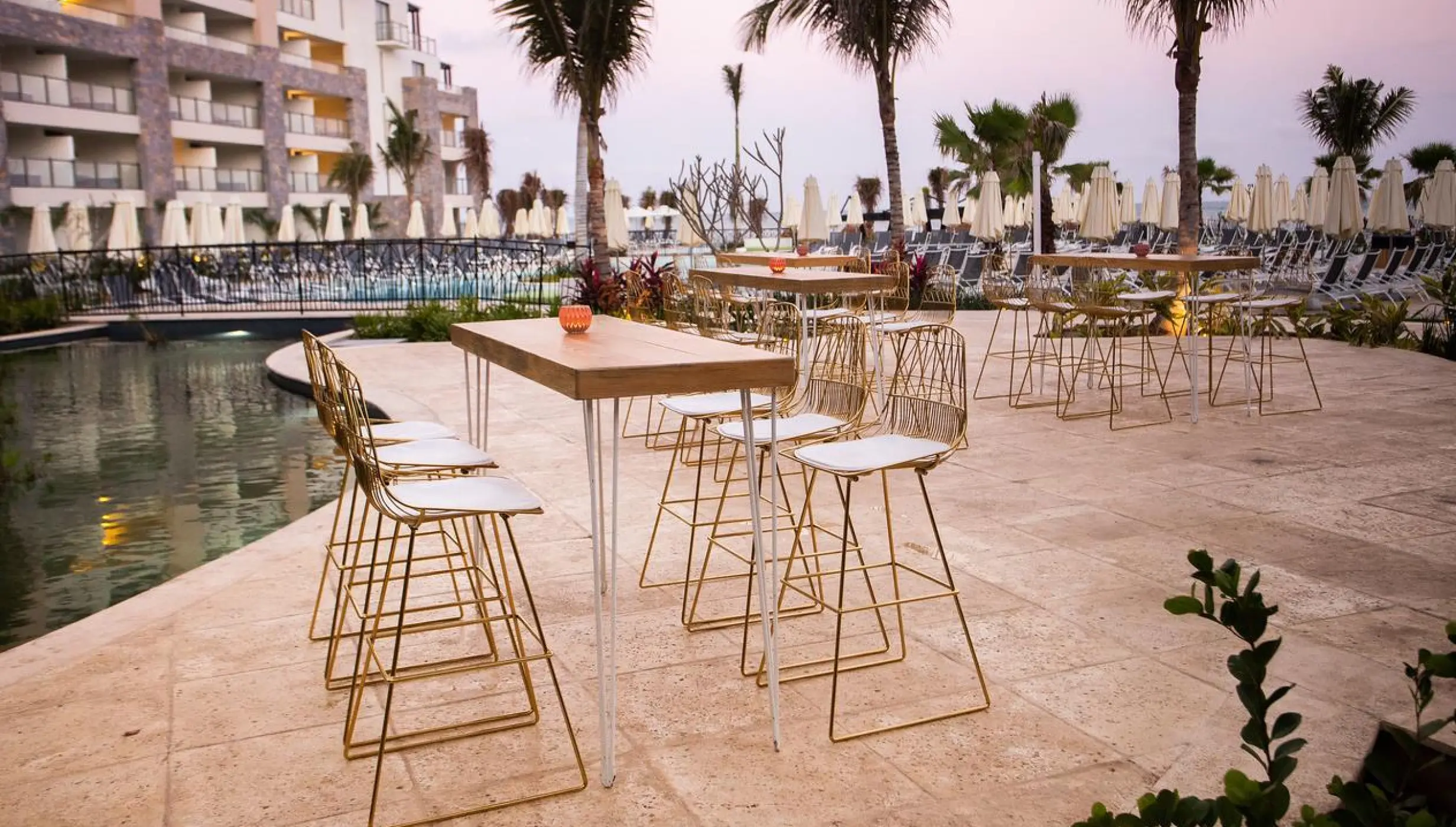 Cocktail tables and gold chairs on the fishpond terrace at Dreams Natura, Riviera Maya