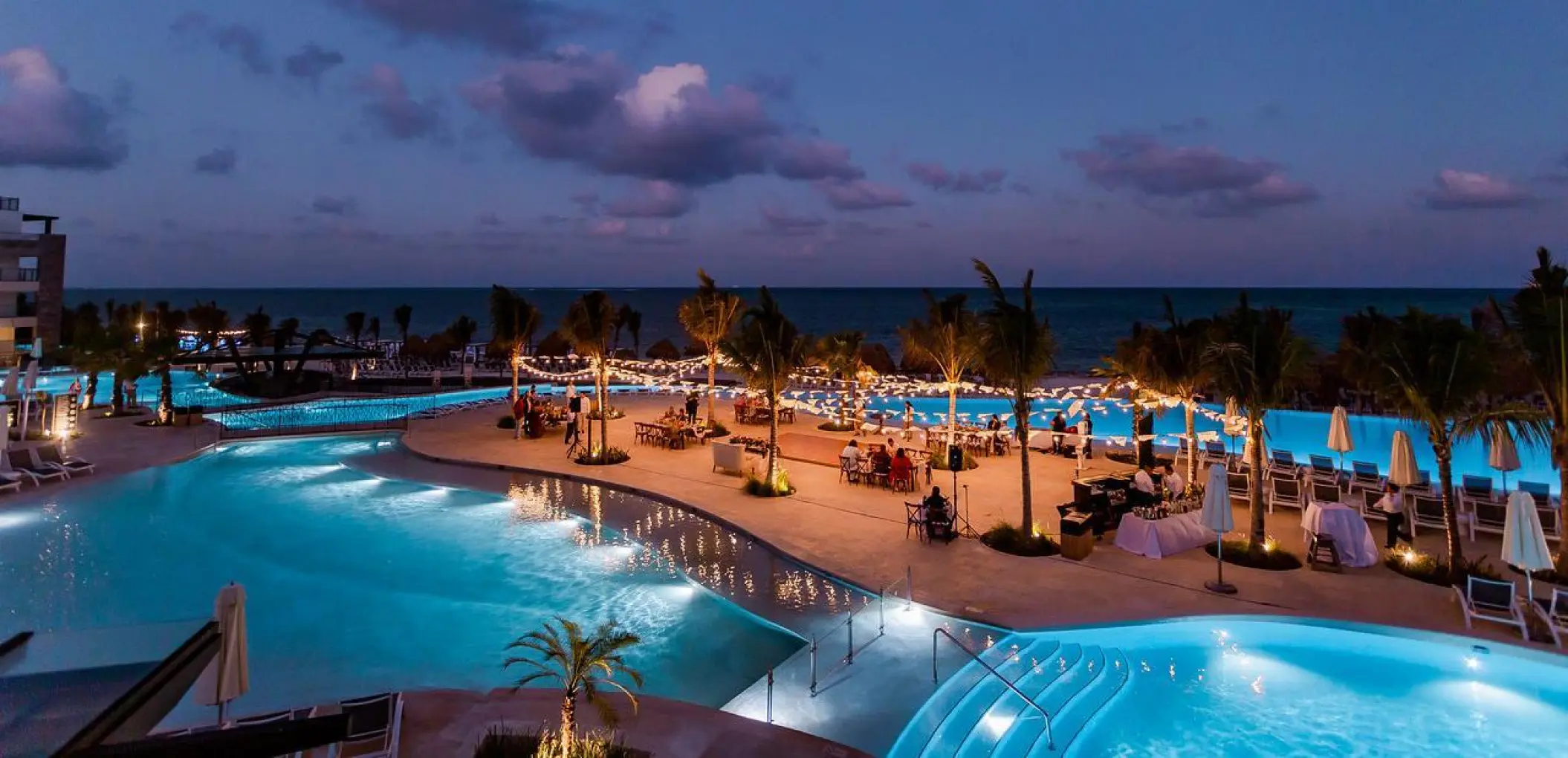 Evening wedding reception with string lights on the pool terrace at Dreams Natura, Riviera Maya