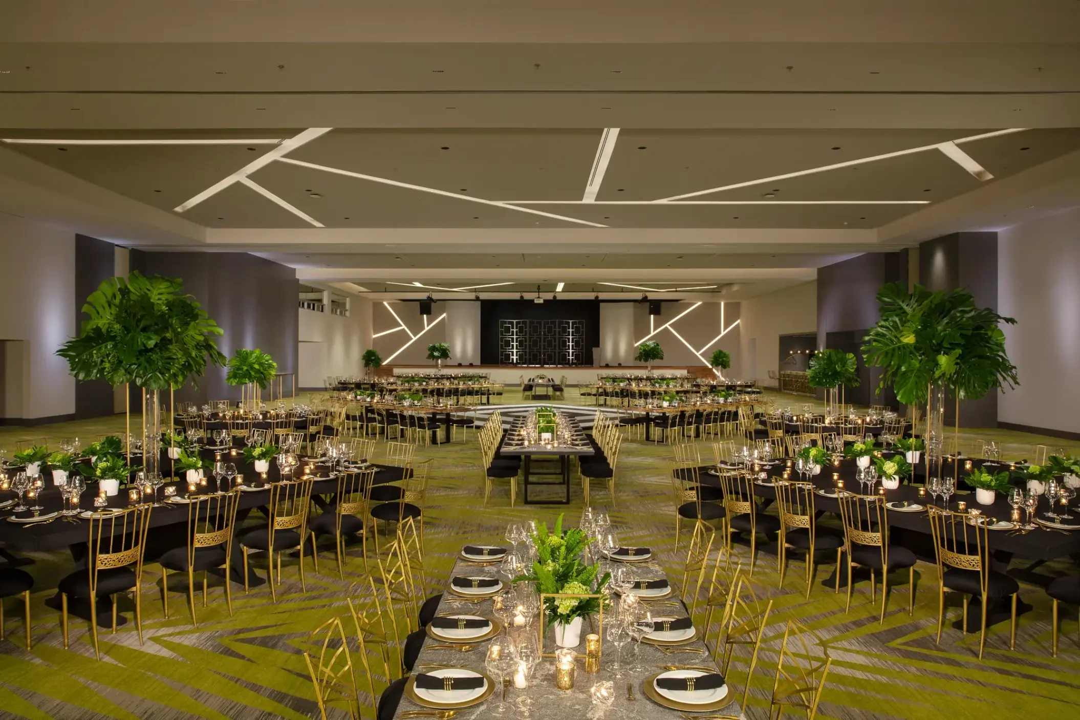 Indoor wedding reception setup with gold chairs and greenery centerpieces at Dreams Natura, Riviera Maya