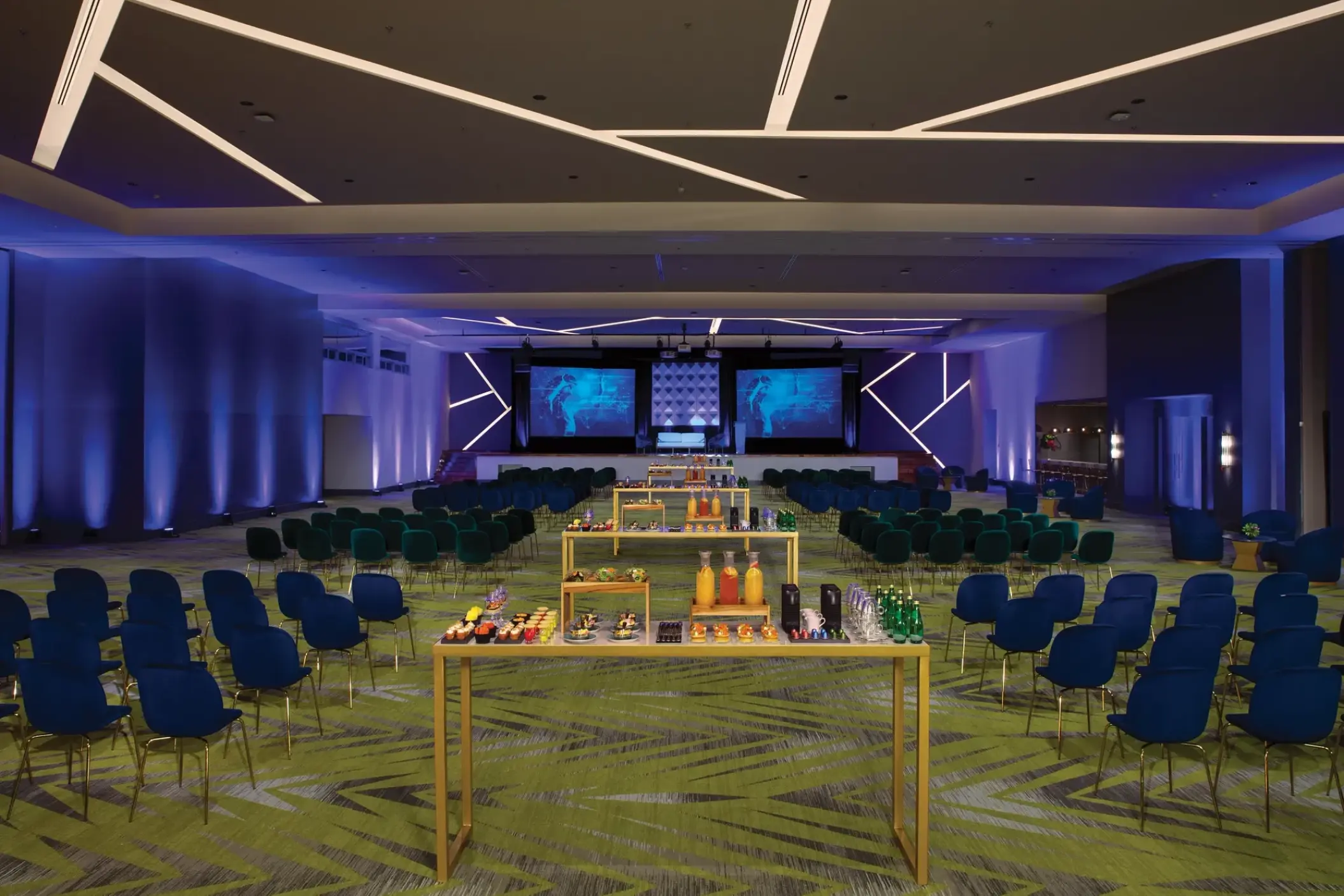 Indoor ballroom wedding reception setup with blue lighting and modern décor at Dreams Natura, Riviera Maya