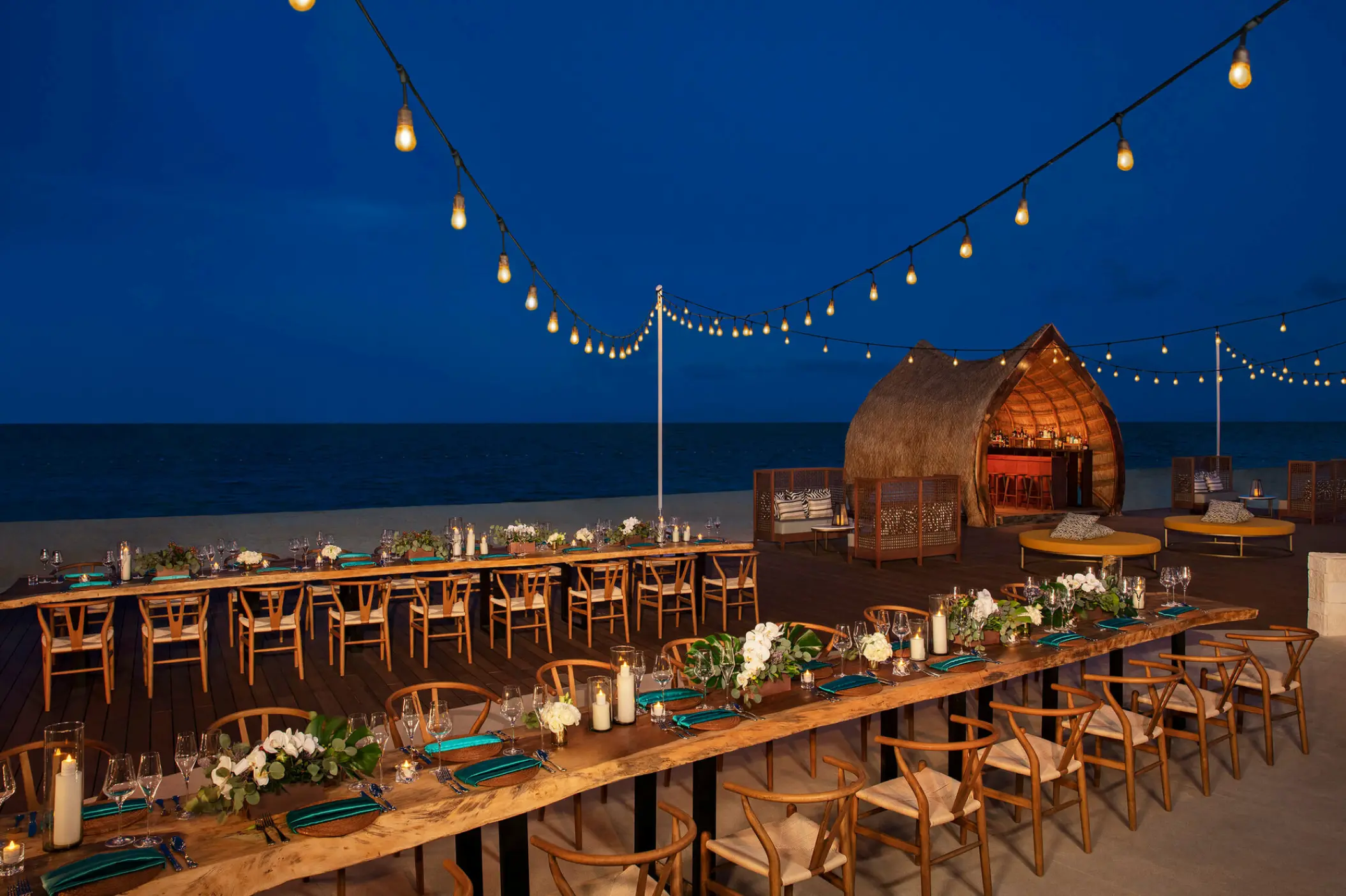 Beachfront wedding reception tables under string lights at Dreams Natura, Riviera Maya