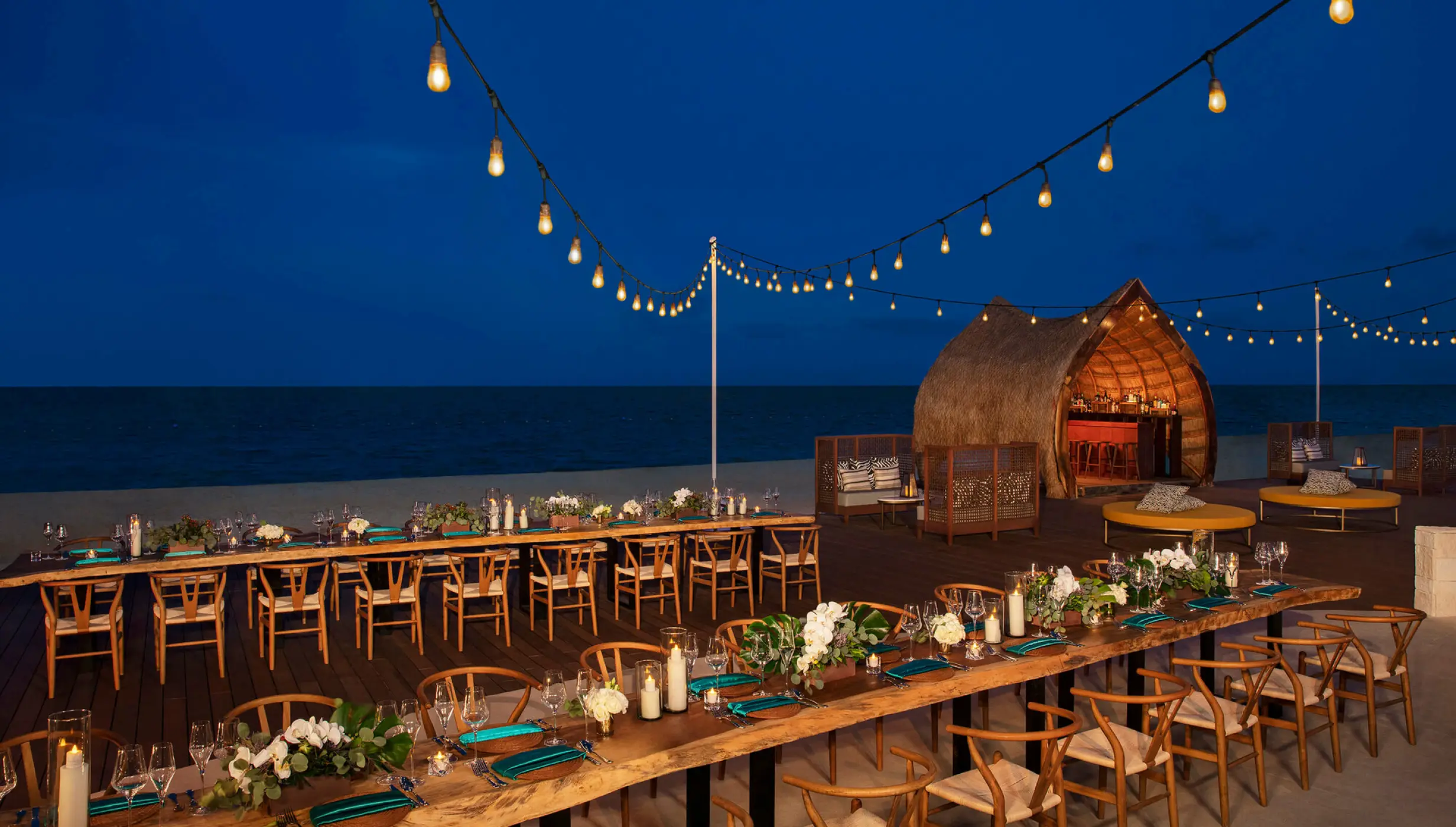 Beachfront wedding reception tables under string lights at Dreams Natura, Riviera Maya