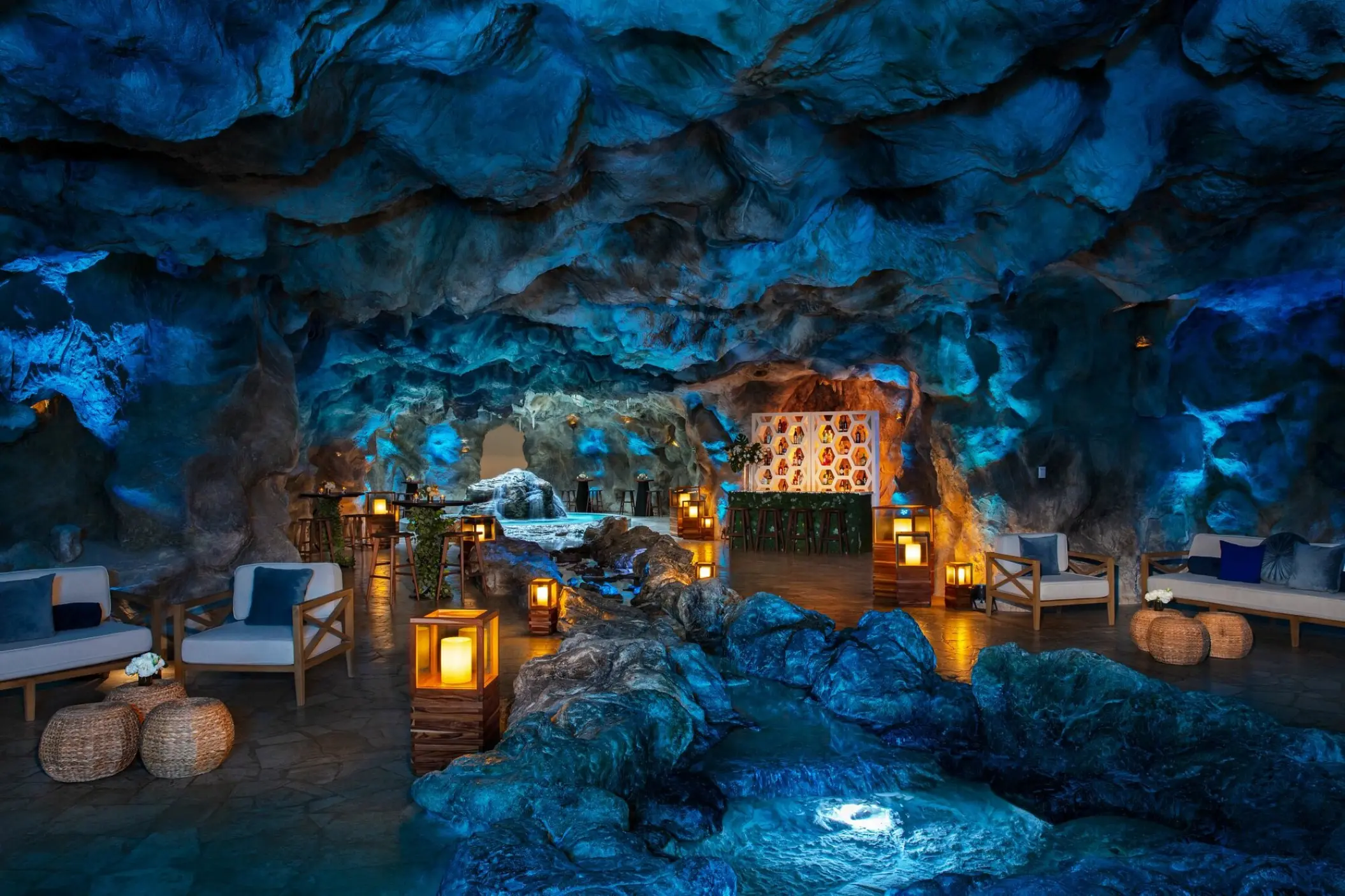 Cenote cocktail room with blue lighting and lounge seating at Dreams Natura