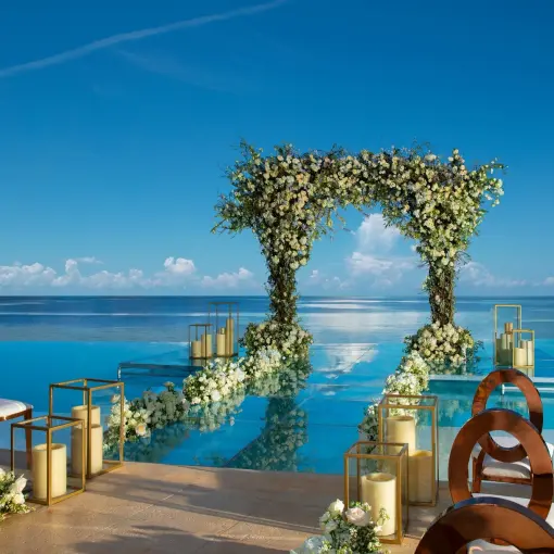 Floral wedding arch on an infinity pool platform overlooking the ocean at Dreams Natura