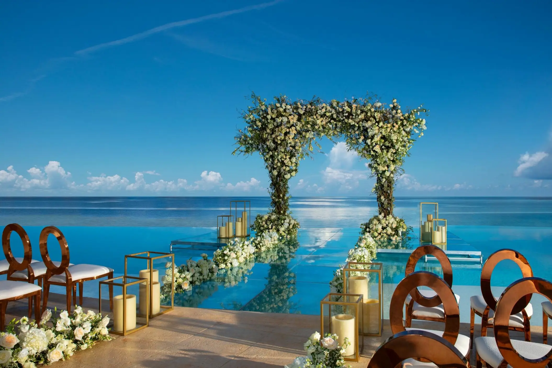 Floral wedding arch on an infinity pool platform overlooking the ocean at Dreams Natura
