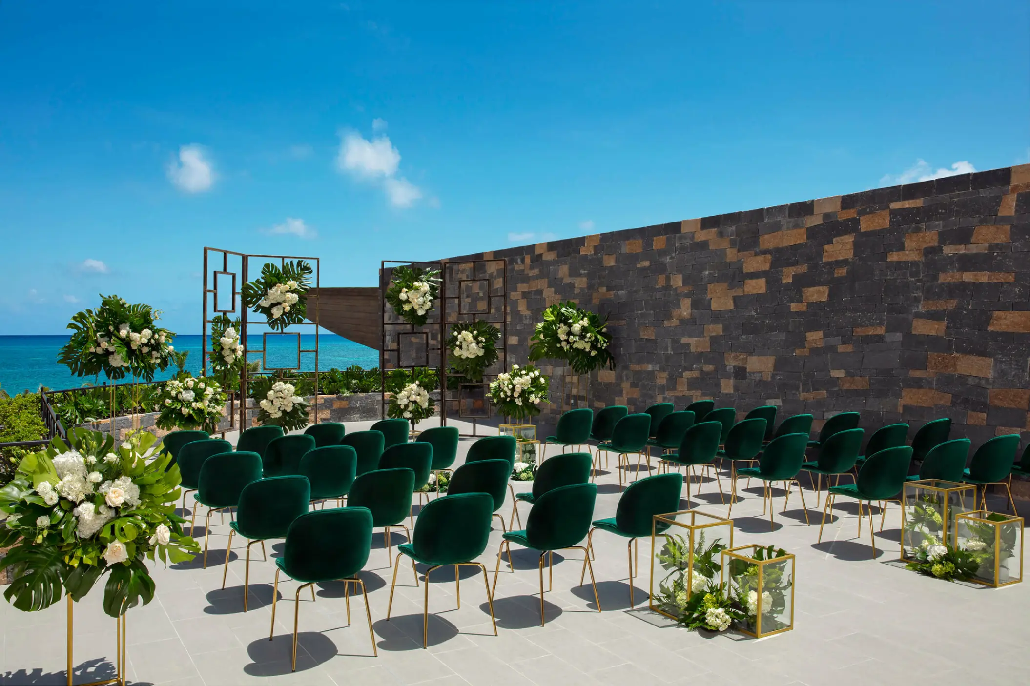 Terrace wedding ceremony at Dreams Natura with green velvet chairs and white floral arrangements