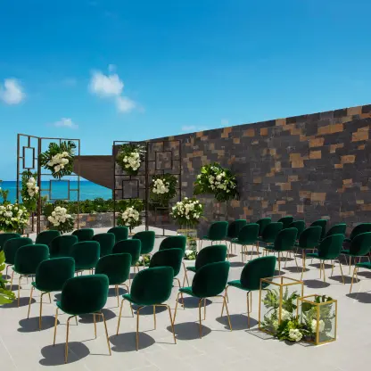 Terrace wedding ceremony with green velvet chairs and white floral pillars at Dreams Natura, Riviera Maya