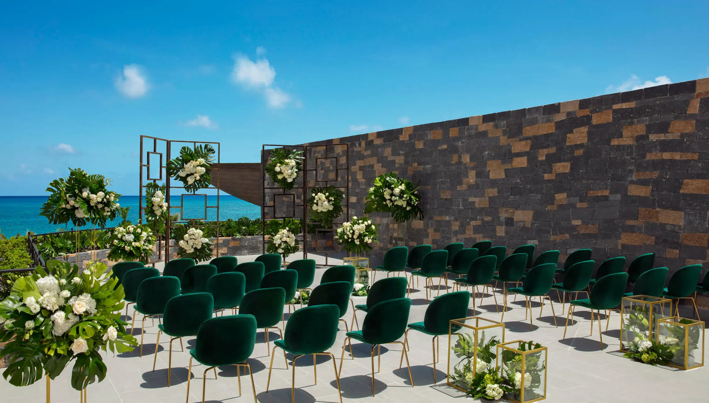 Terrace wedding ceremony with green velvet chairs and white floral pillars at Dreams Natura, Riviera Maya