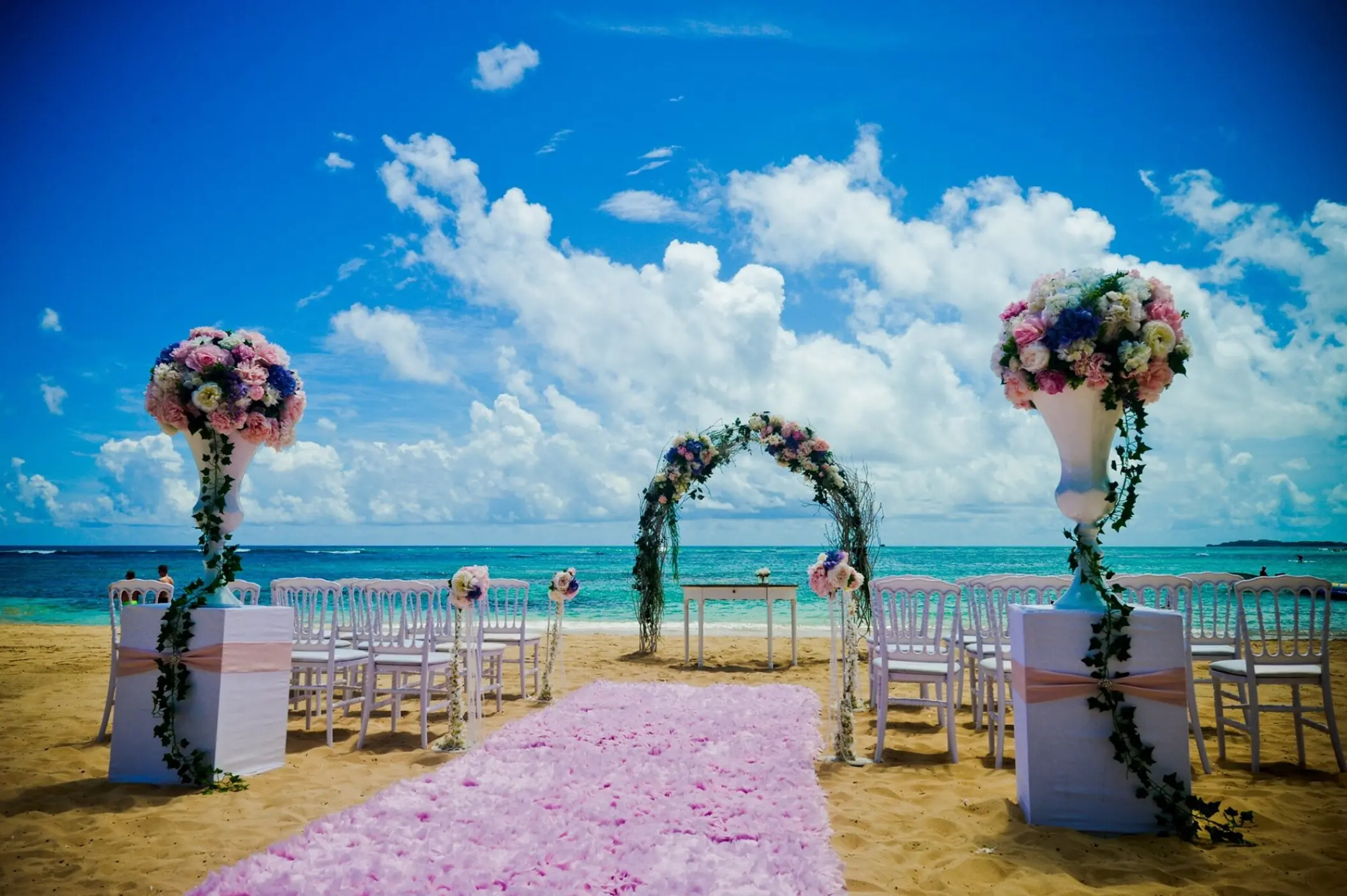 Beachfront wedding ceremony with a floral arch and pink petal runner at Dreams Onyx, Punta Cana