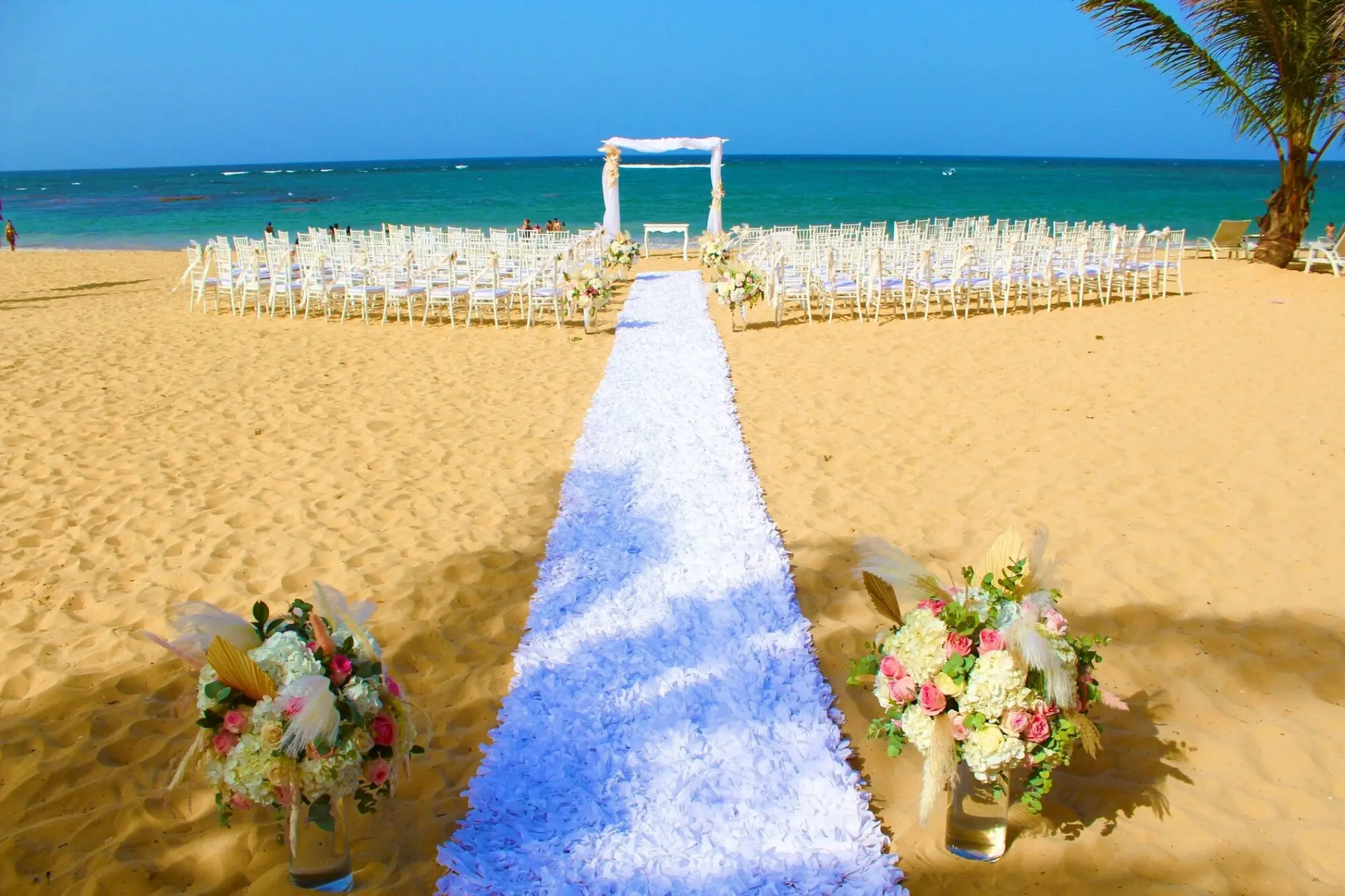 Beachfront wedding ceremony with white aisle runner and floral arrangements at Dreams Onyx, Punta Cana
