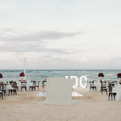 Beachfront wedding reception setup with string lights and white tables at Dreams Onyx, Punta Cana