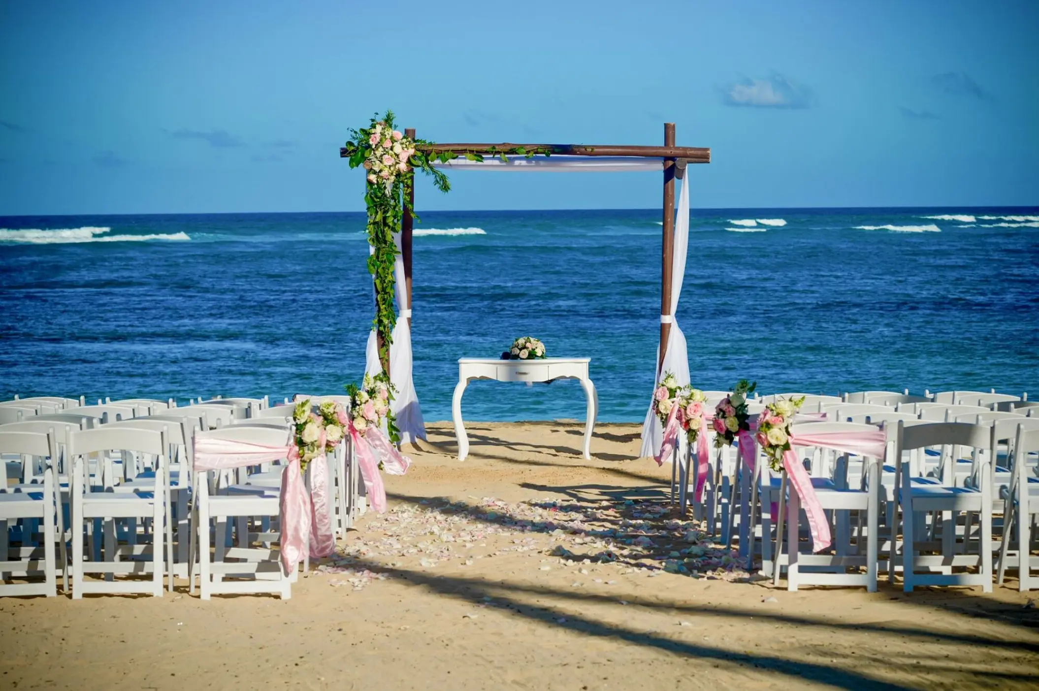 Beachfront wedding ceremony with a floral wooden arch at Dreams Onyx, Punta Cana