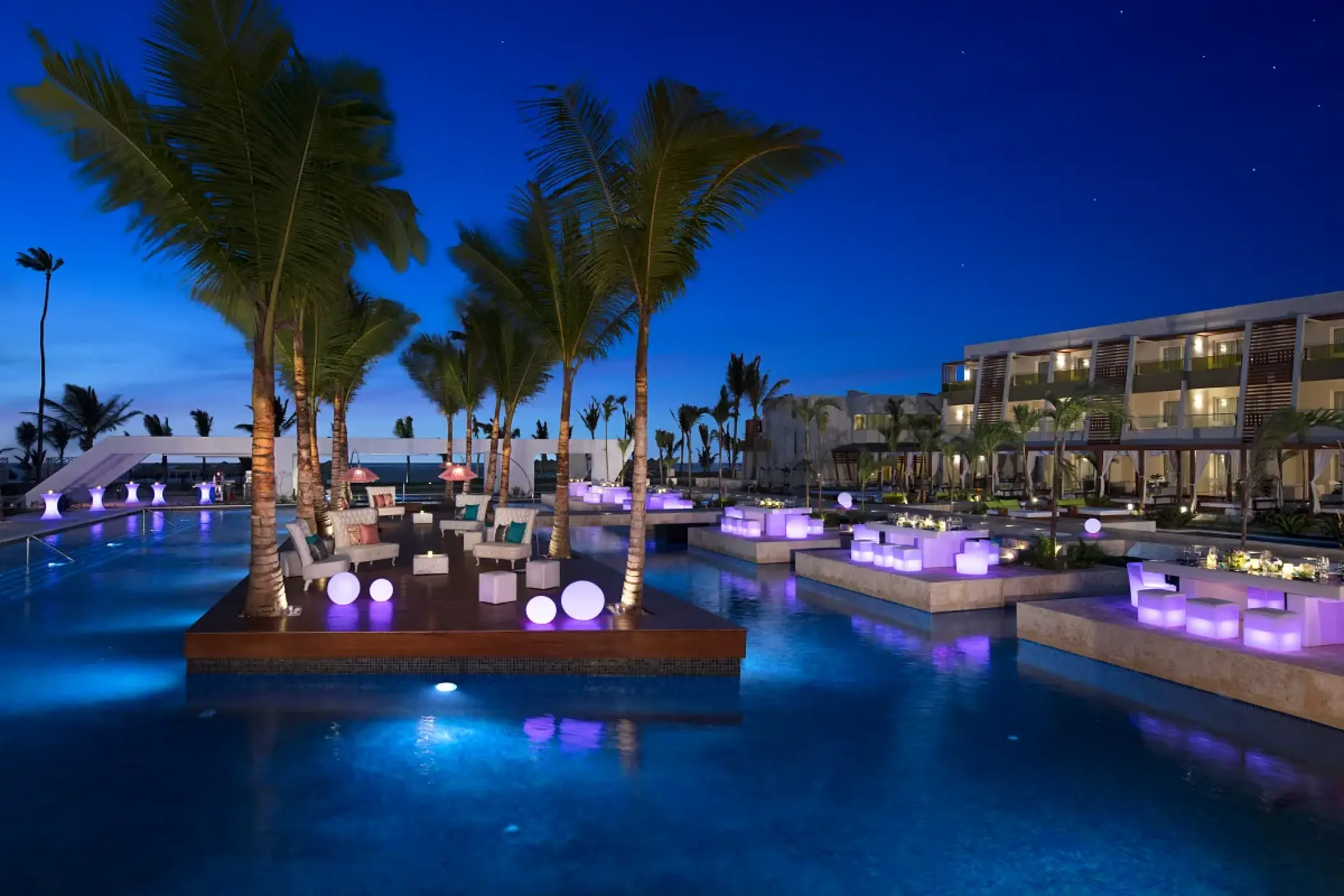 Evening poolside gala dinner setup with purple glowing seating at Dreams Onyx, Punta Cana