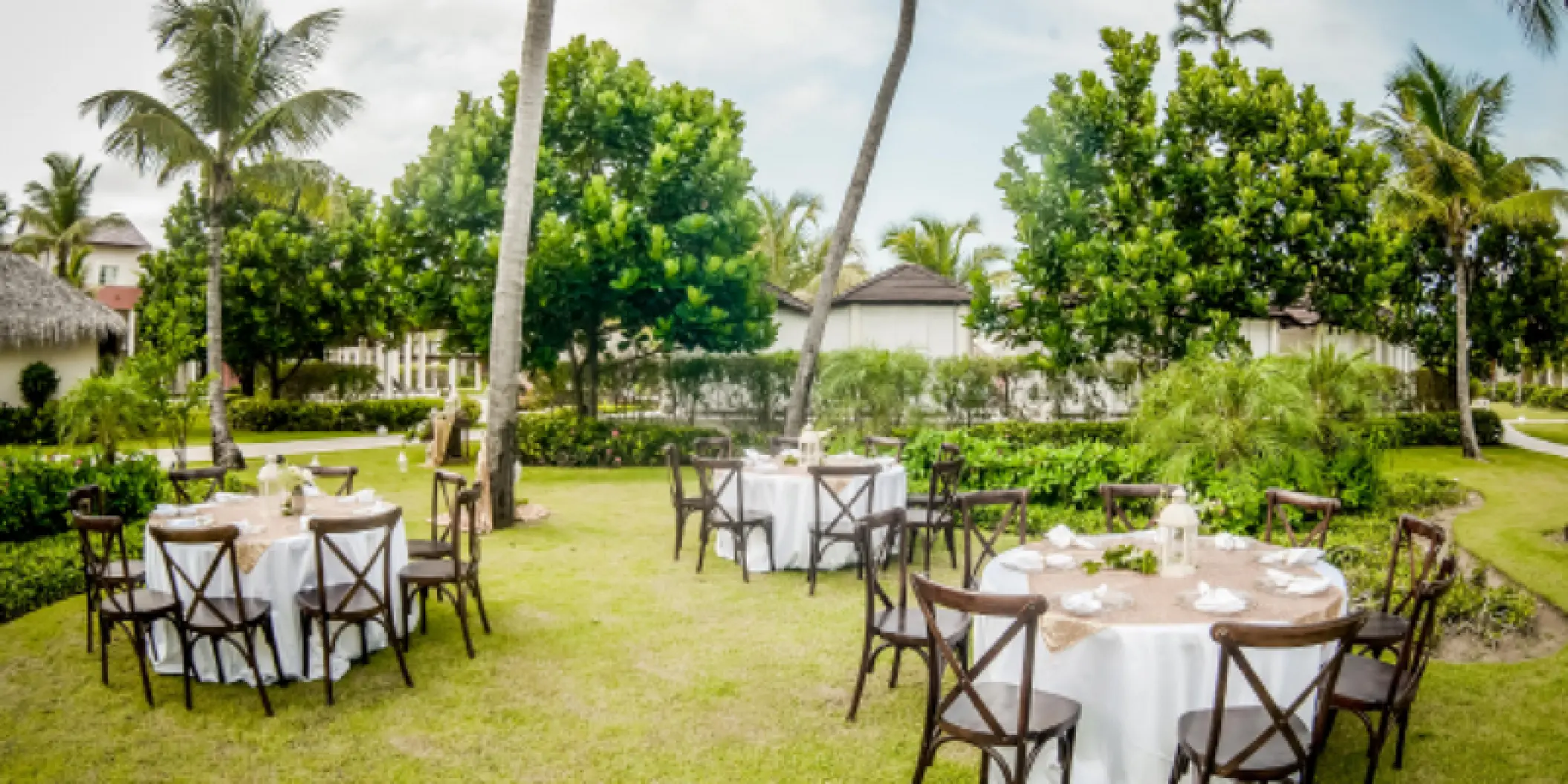 Garden wedding reception with round tables and cross-back chairs at Dreams Onyx, Punta Cana