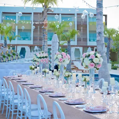 Long wedding reception table with floral centerpieces by the pool at Dreams Onyx, Punta Cana
