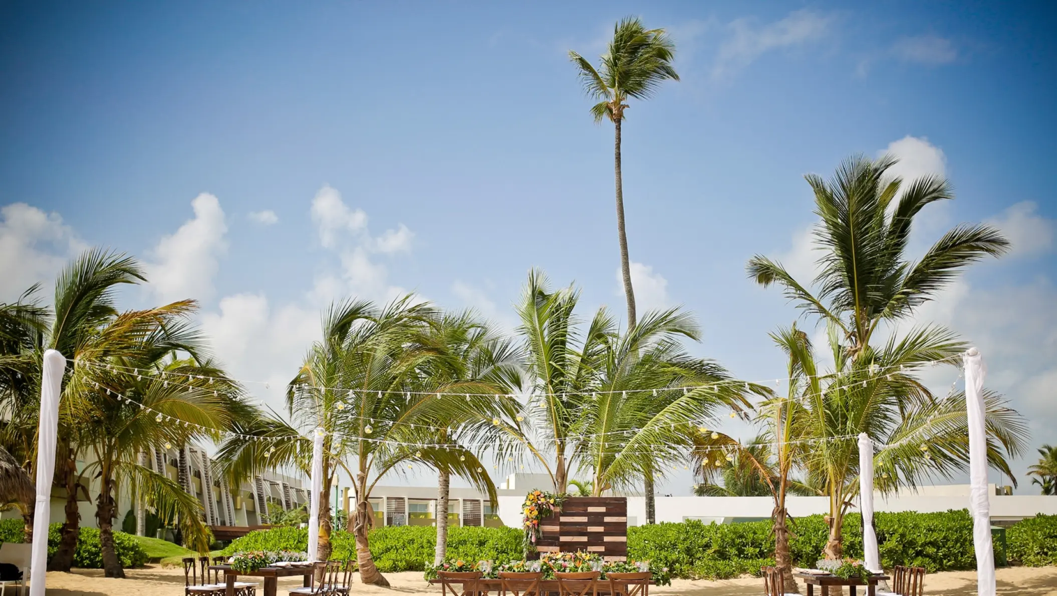 Outdoor wedding reception setup with wooden tables and palm trees at Dreams Onyx, Punta Cana