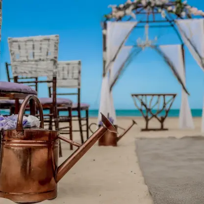 Beach wedding ceremony at Dreams Onyx, Punta Cana with copper watering can decor and white draped gazebo