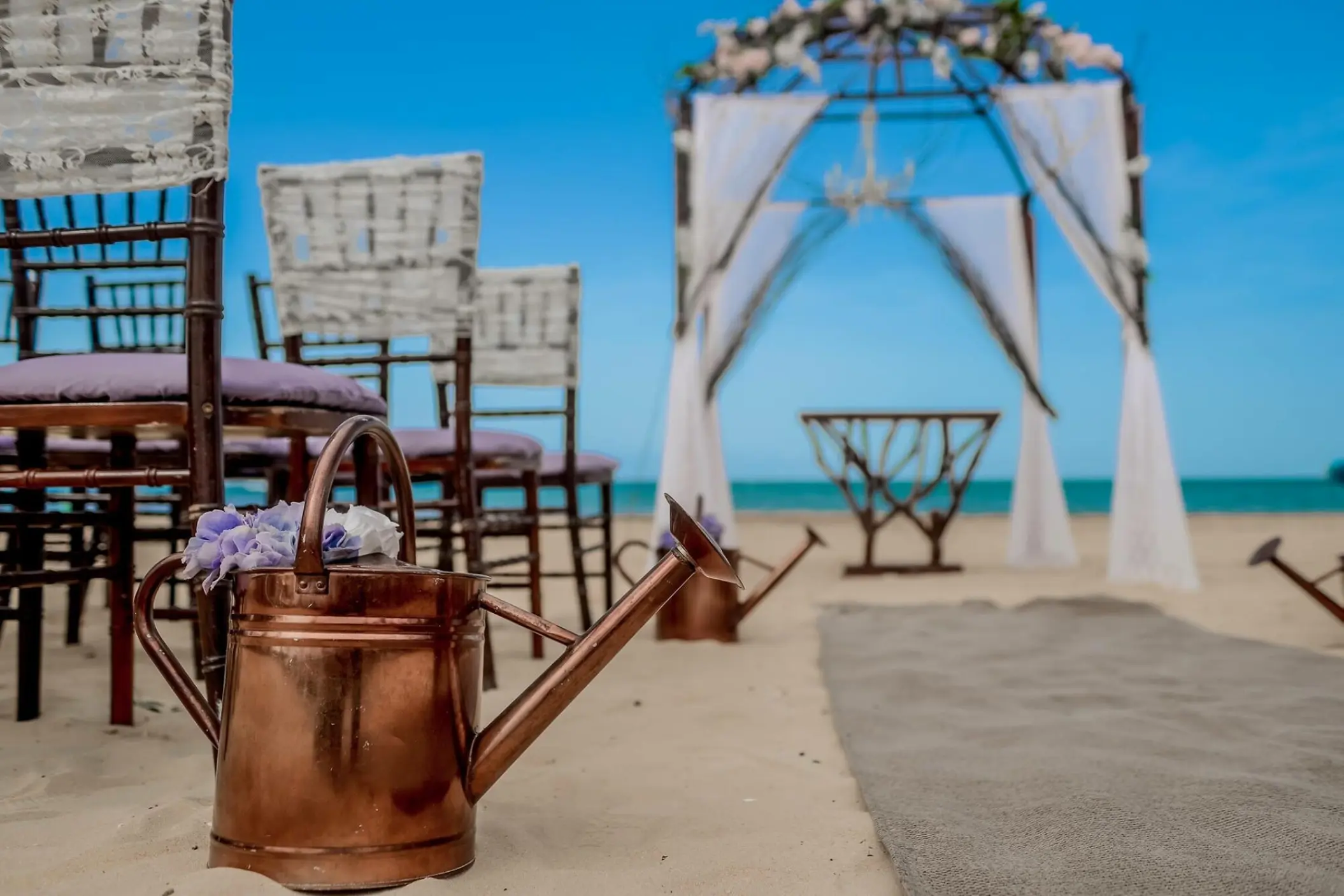 Beach wedding ceremony at Dreams Onyx, Punta Cana with copper watering can decor and white draped gazebo