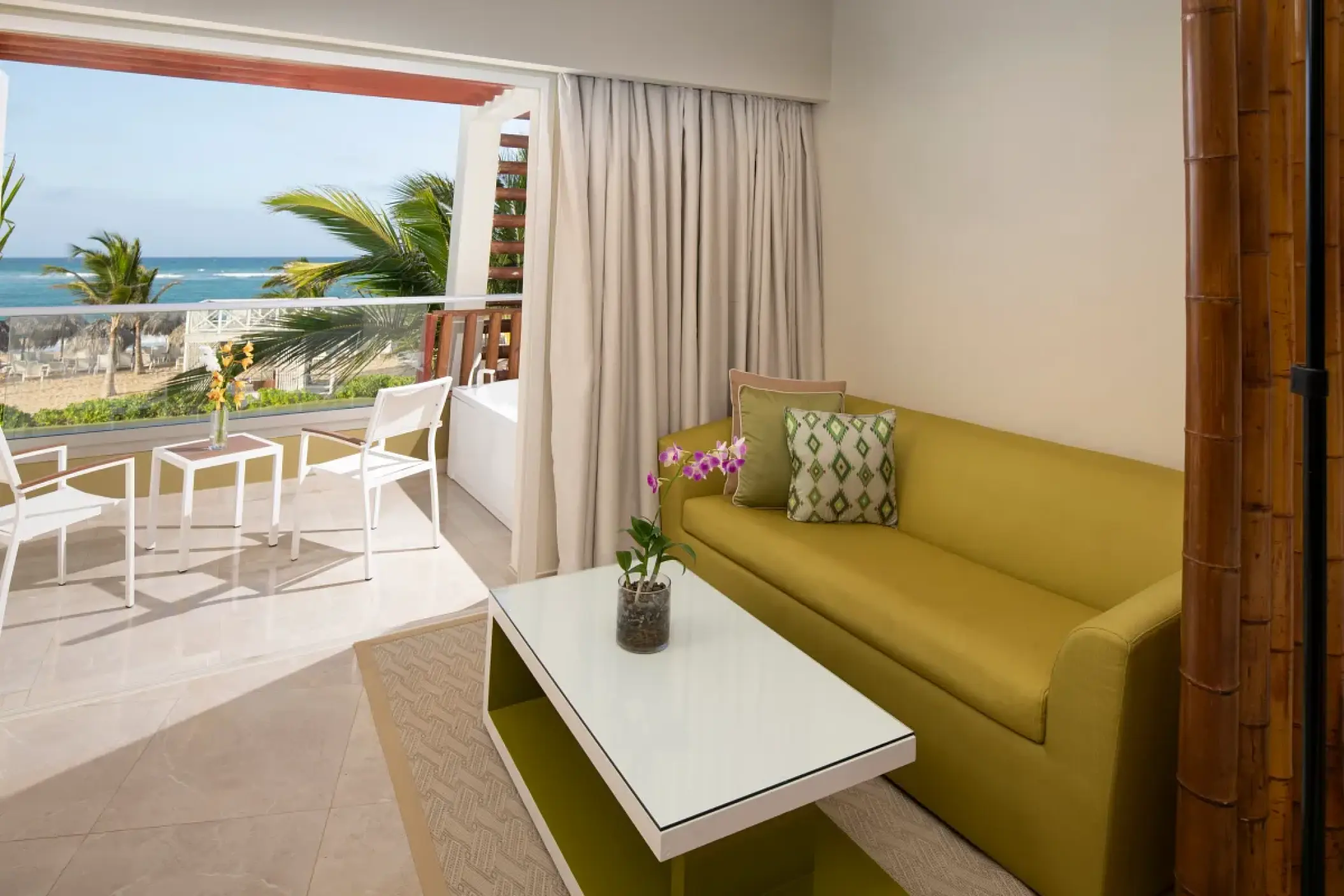 Terrace suite living area with a green sofa and ocean view balcony at Dreams Onyx, Punta Cana