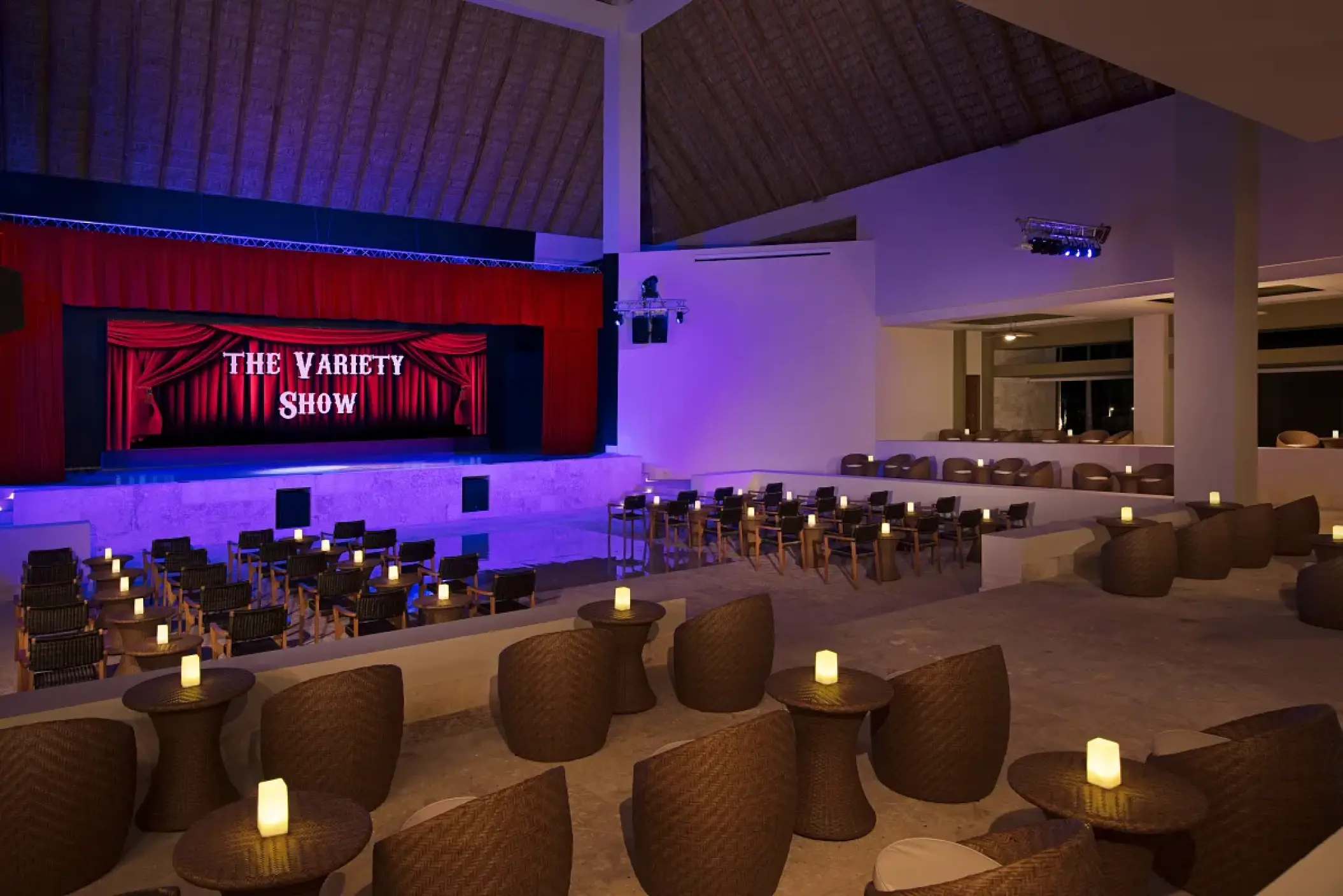 Indoor theater with red stage curtains and candlelit lounge seating at Dreams Onyx, Punta Cana