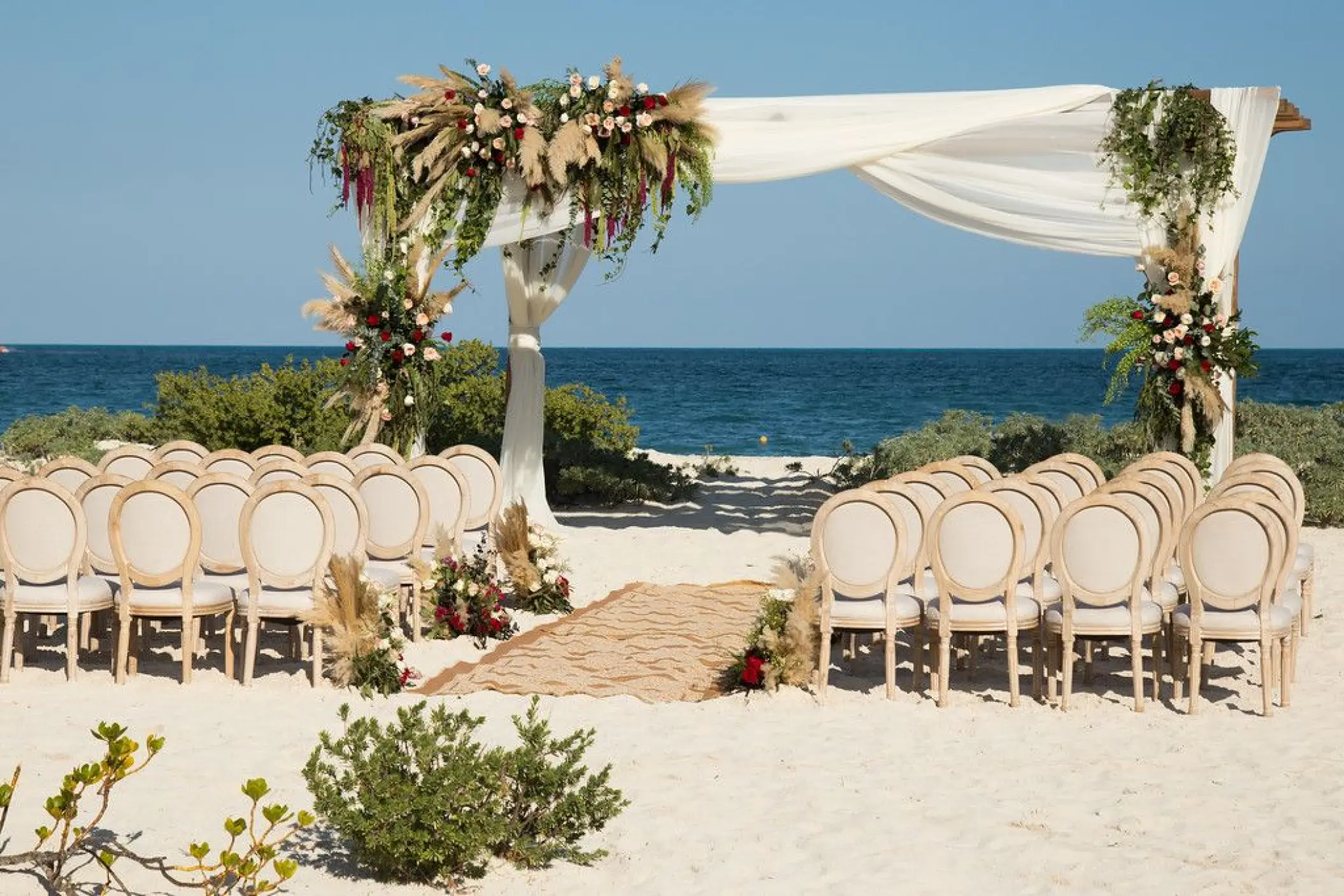 Beachfront wedding ceremony with floral arch and rows of chairs at Dreams Playa Mujeres, Cancun