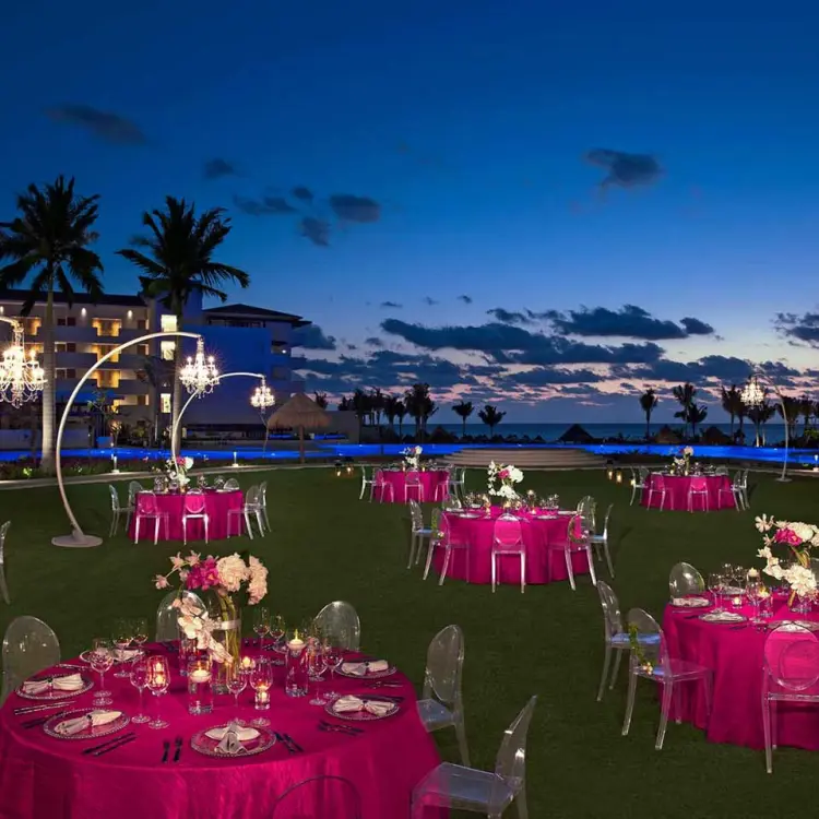 Evening wedding reception with pink linens on the lawn at Dreams Playa Mujeres, Cancun