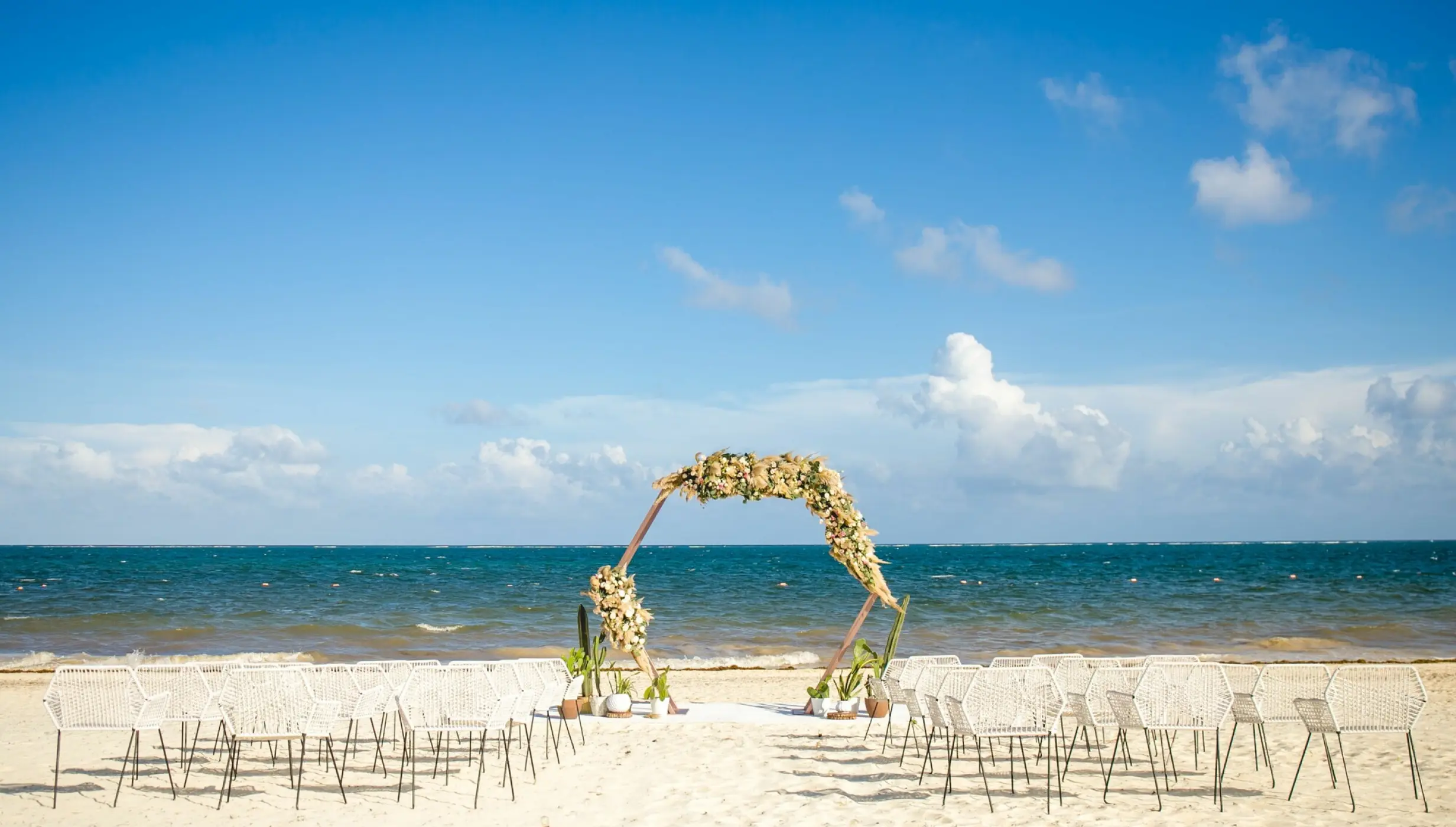 Beachfront wedding ceremony with a floral hexagonal arch at Dreams Riviera Cancun, Riviera Maya