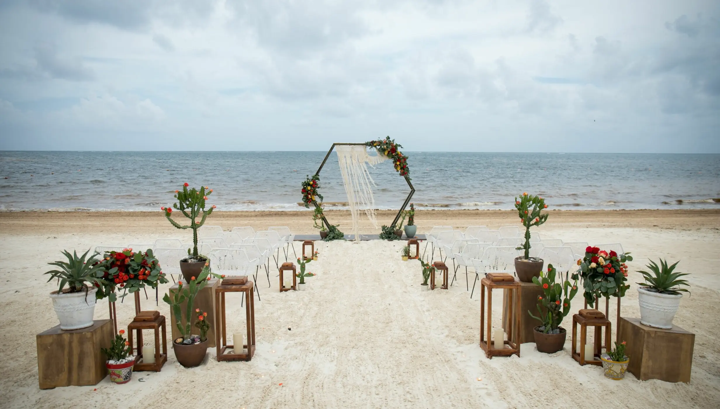 Beachfront wedding ceremony with a macrame arch and cactus decor at Dreams Riviera Cancun, Riviera Maya