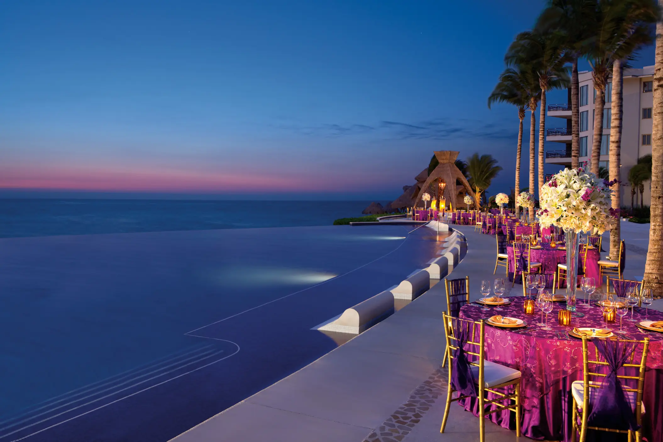 Outdoor wedding reception with purple linens by the infinity pool at Dreams Riviera Cancun, Riviera Maya