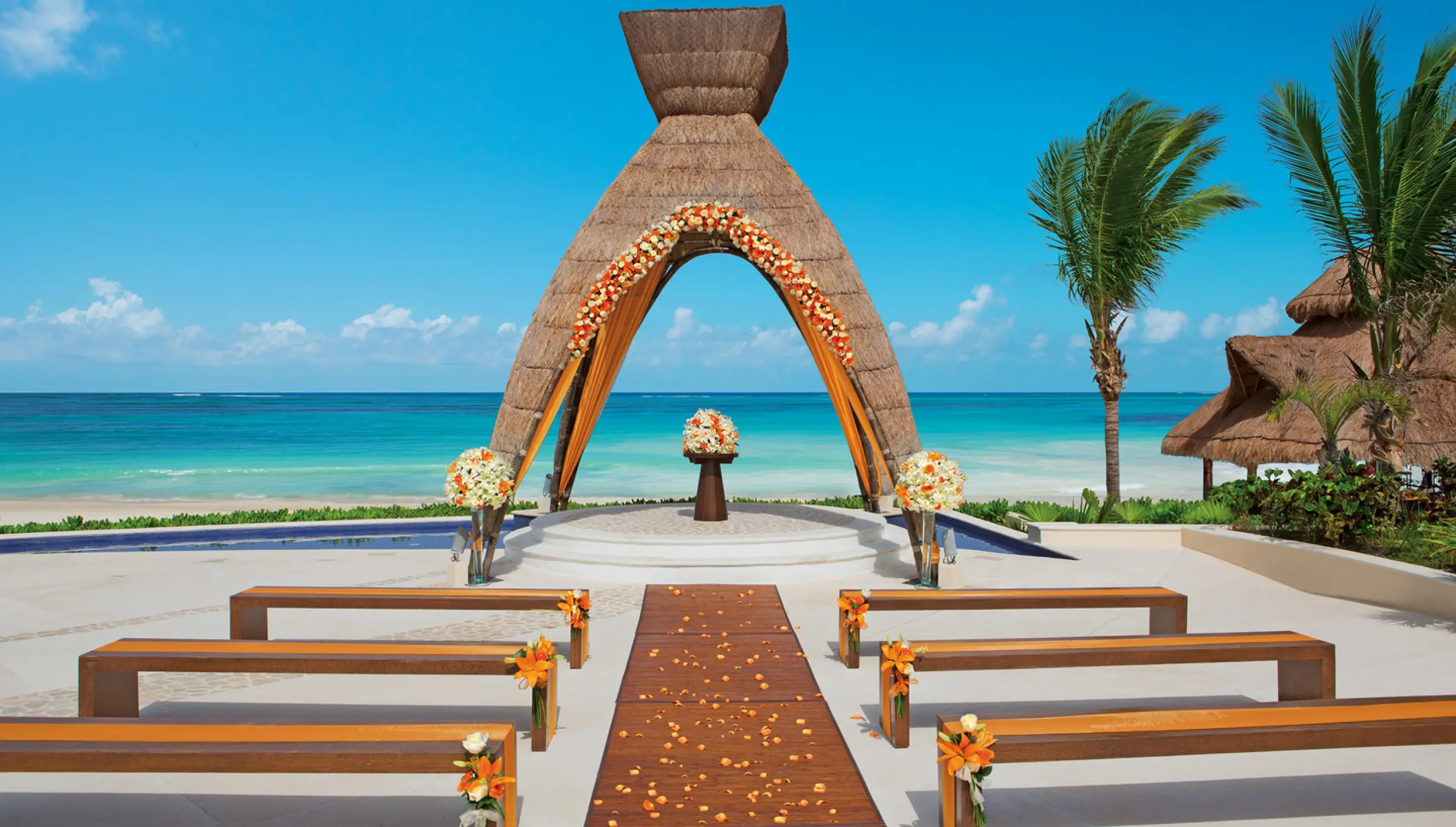 Thatch gazebo wedding ceremony with wooden benches at Dreams Riviera Cancun, Riviera Maya